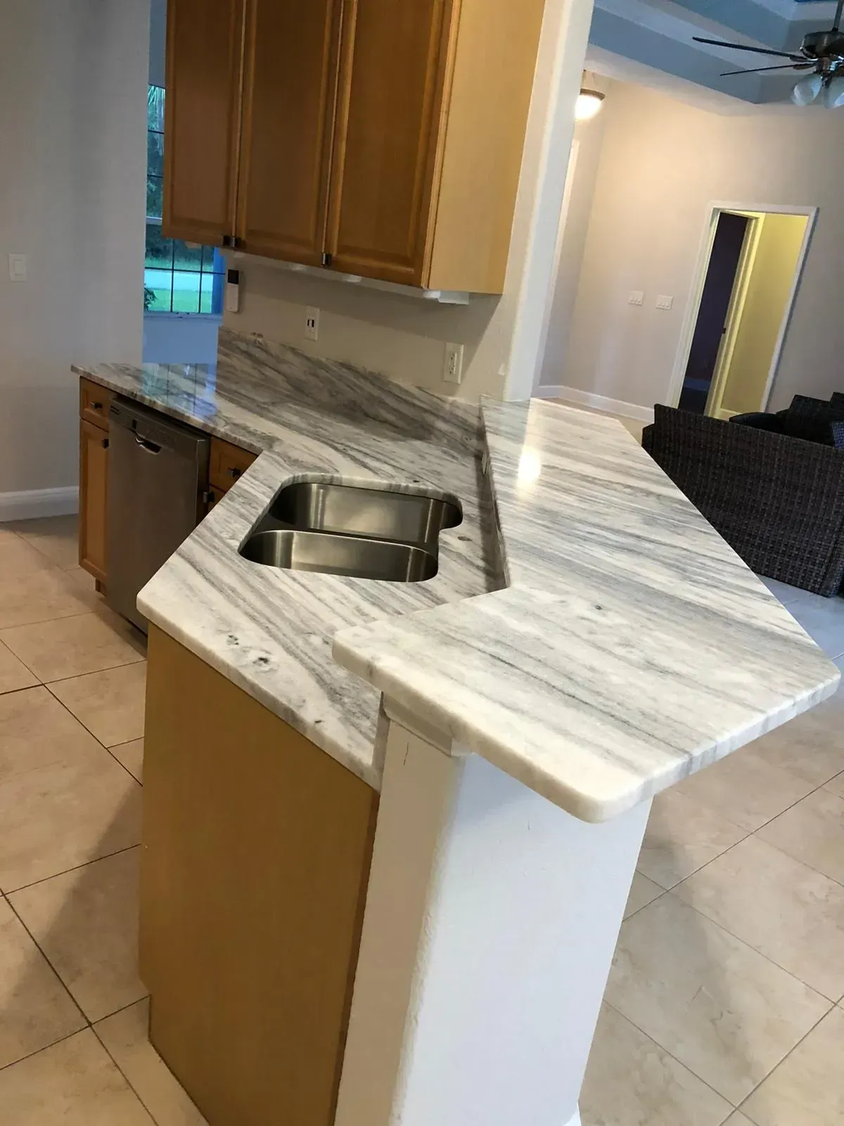 Kitchen island with a stainless sink and white marble countertop in a bright home interior
