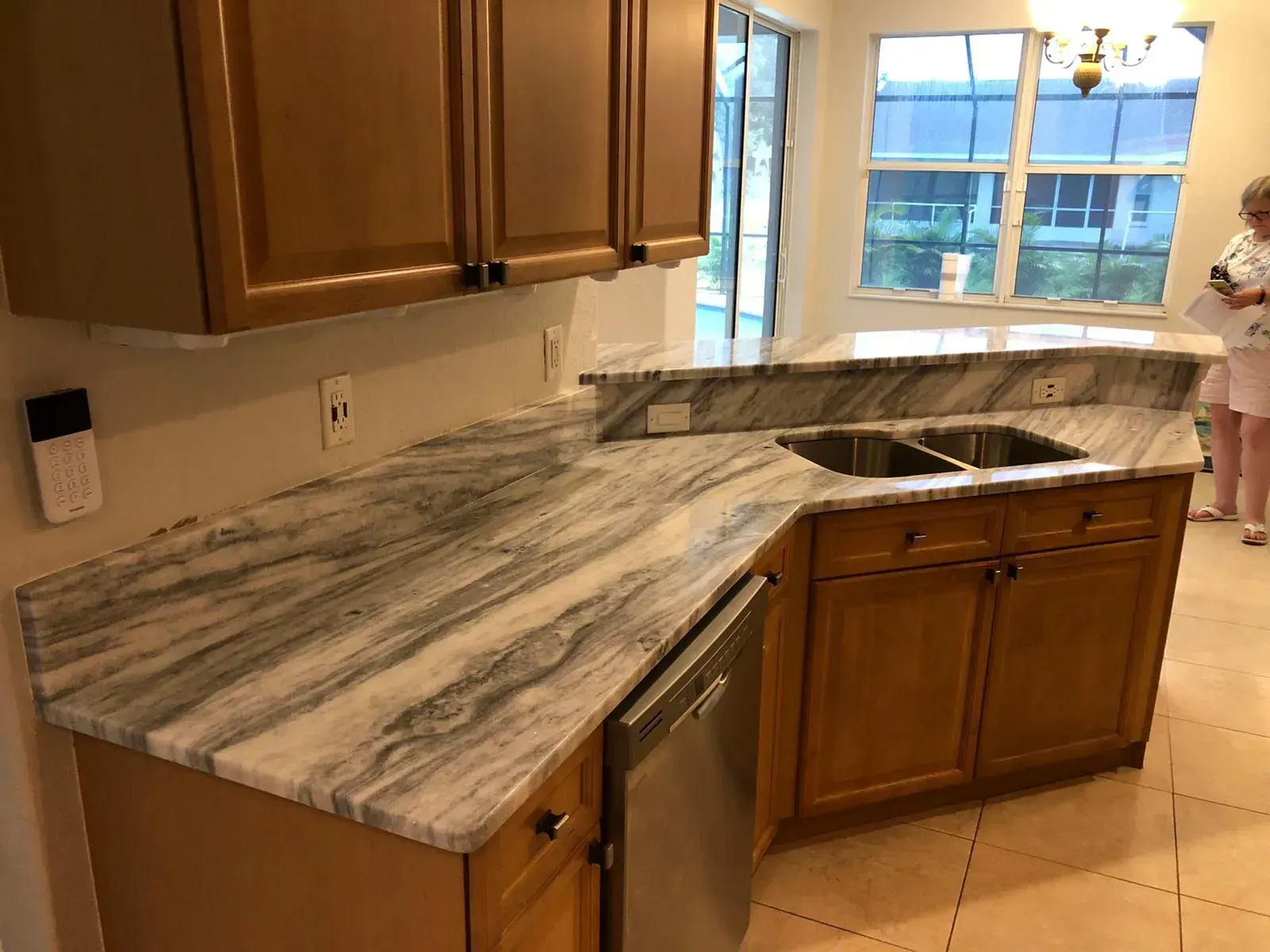 Kitchen with granite countertops, wooden cabinets, stainless dishwasher, and a sink by a window