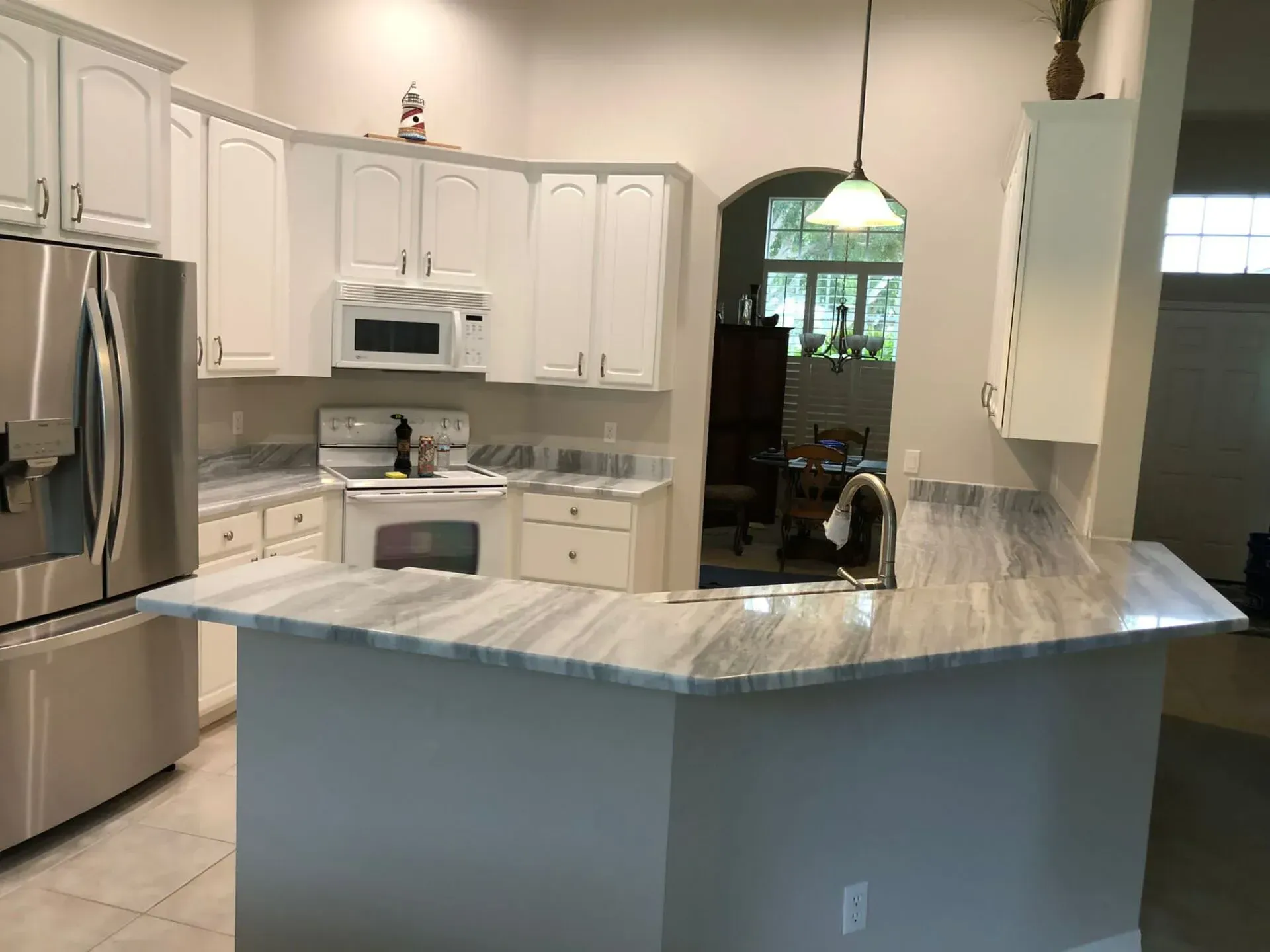 Bright white kitchen with stainless steel appliances and a large blue-gray island