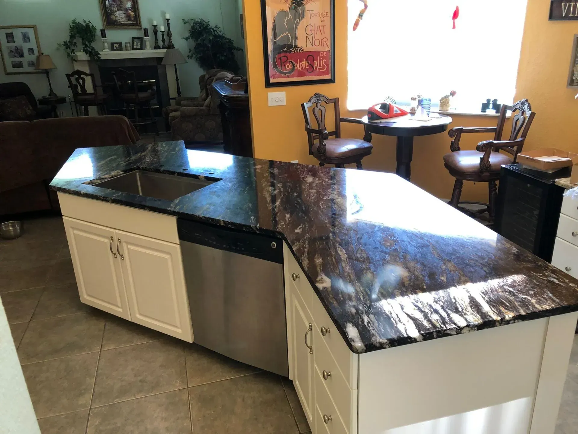 Kitchen island with black granite countertop and white cabinets in a bright, open home interior