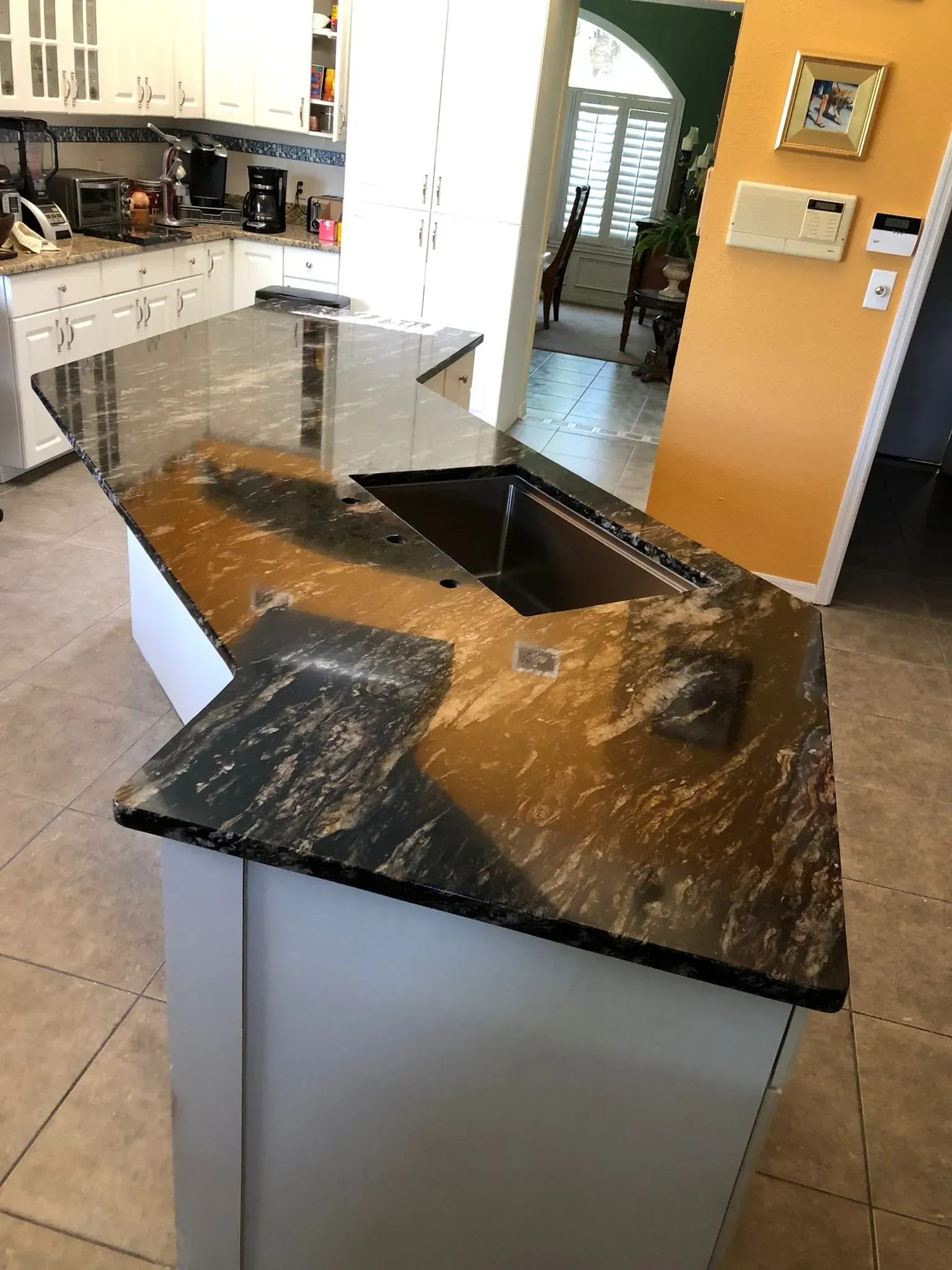 Kitchen island with black granite countertop and sink in a bright, modern kitchen