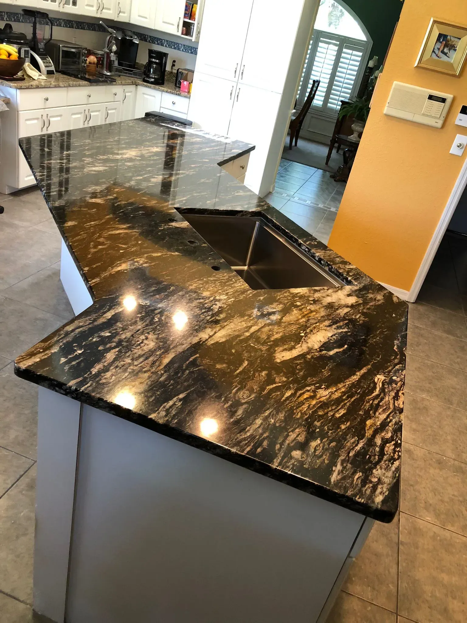 Kitchen island with a black marble countertop and built-in sink in a modern kitchen.