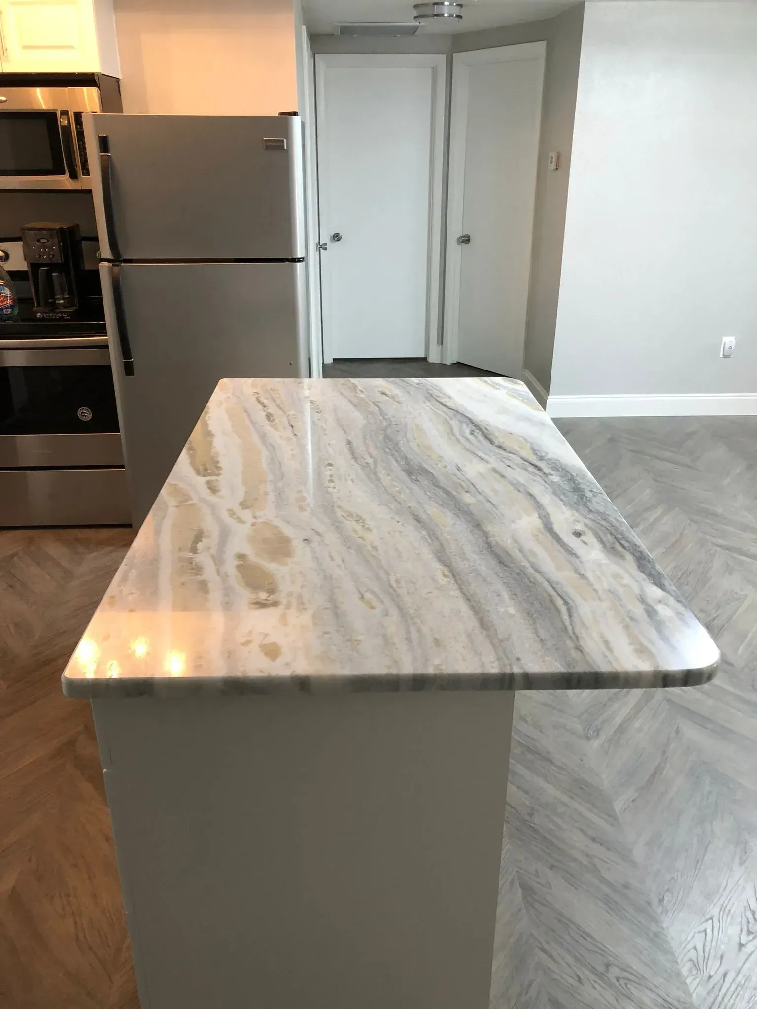 Kitchen island with gray marble countertop in a modern apartment kitchen.