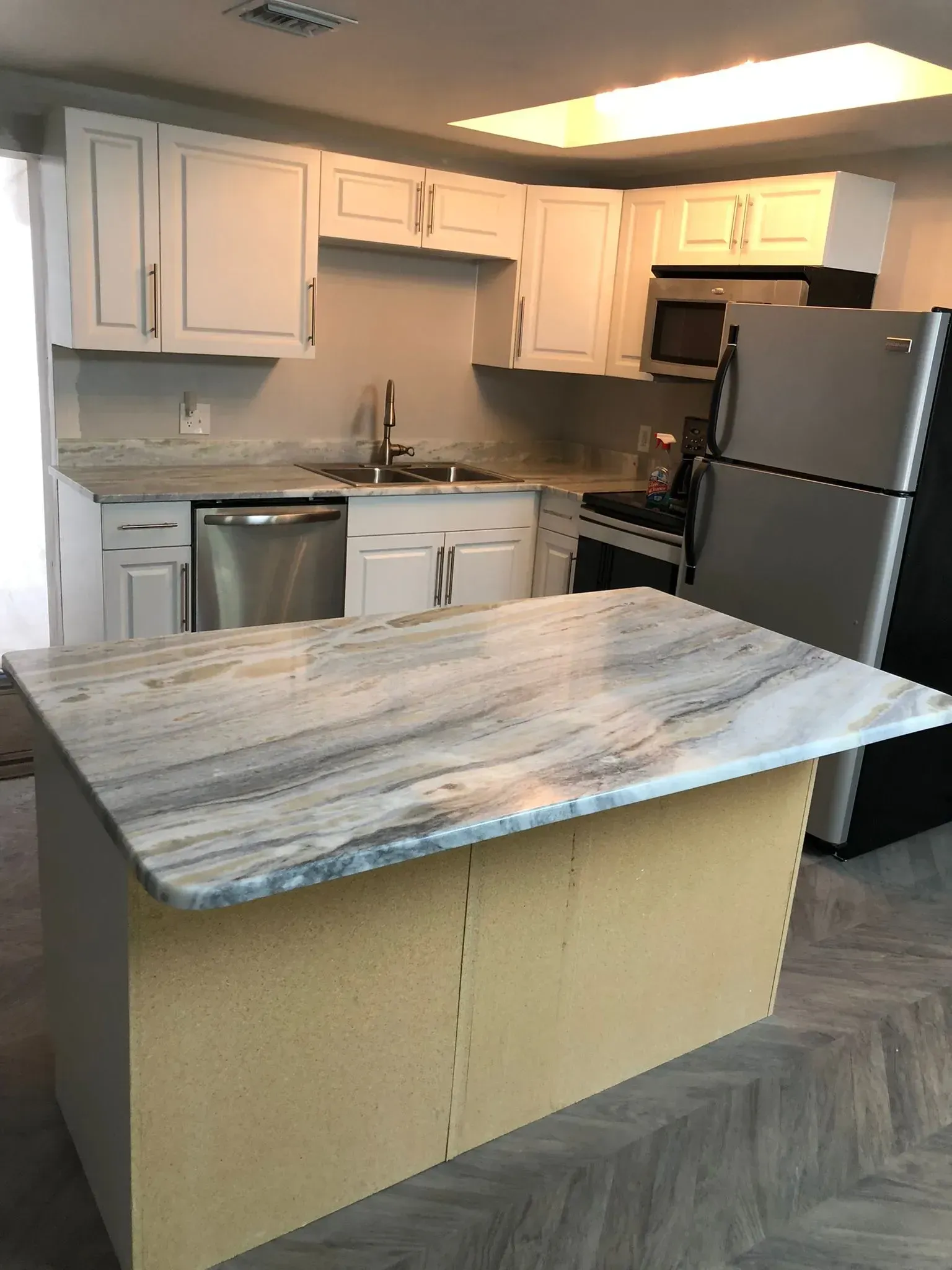 Modern kitchen with white cabinets, stainless appliances, and a marble-look island countertop