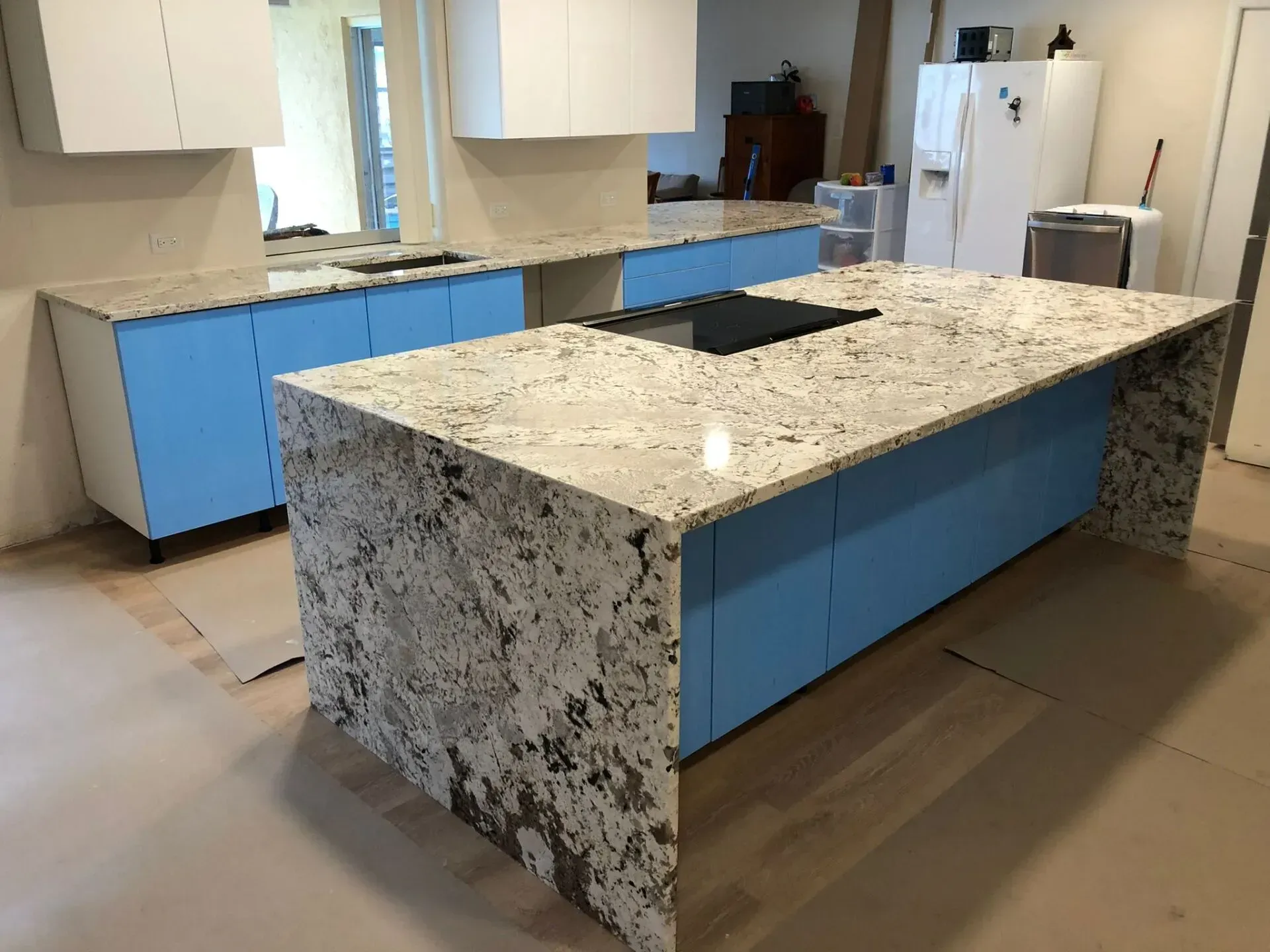 Modern kitchen with blue cabinets, speckled stone island, and open shelving