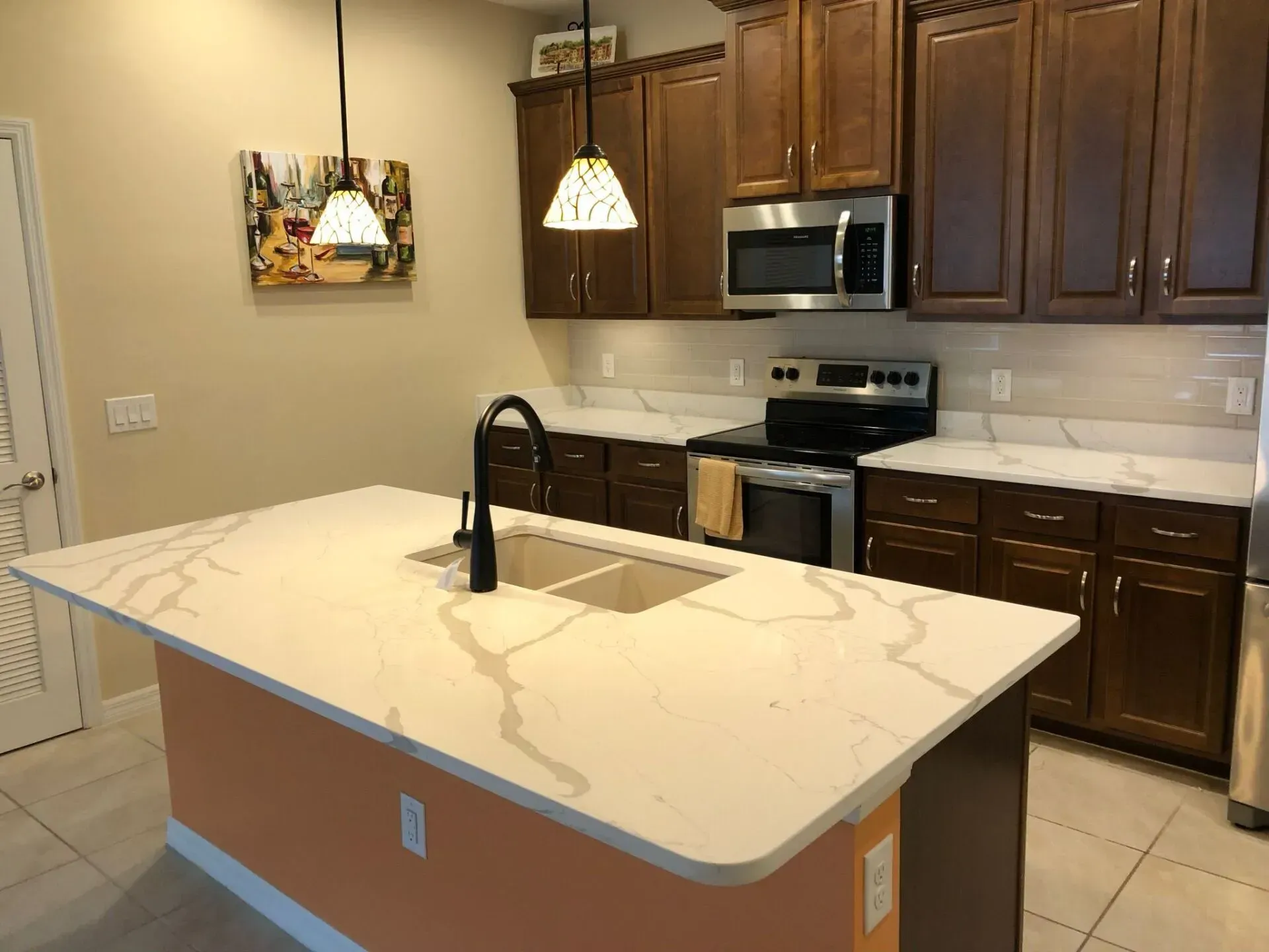 Modern kitchen with a large marble island, dark wood cabinets, stainless steel appliances, and pendant lights