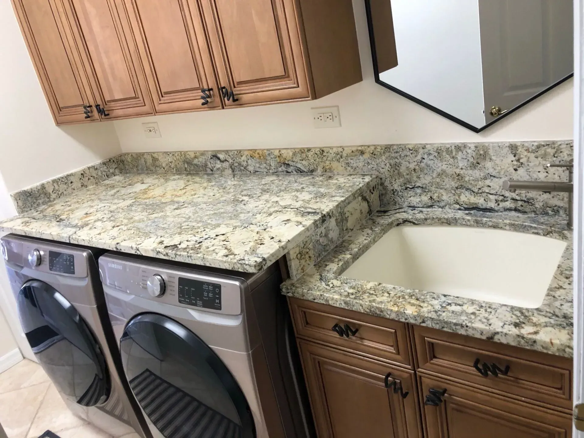 Laundry room with granite countertop, white sink, wood cabinets, and washer and dryer underneath