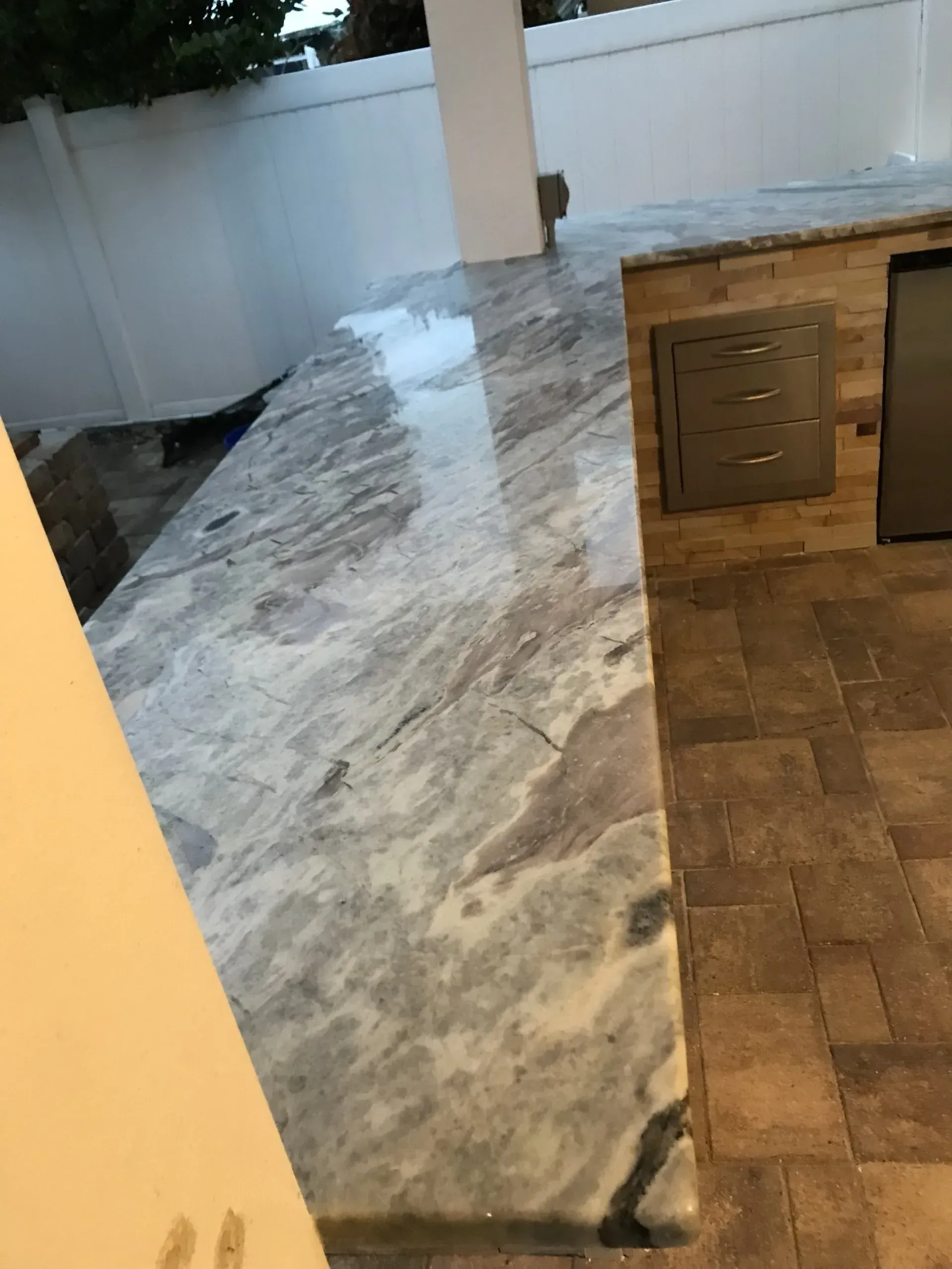 Marble countertop beside a wood-tiled floor and wooden cabinet in a kitchen or bar area