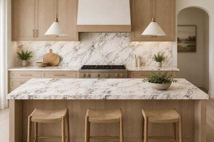 Modern kitchen with marble island, wood cabinets, and three woven stools under pendant lights