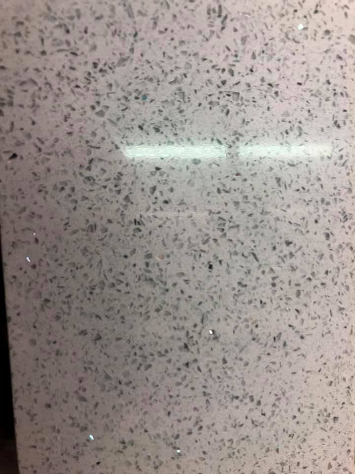 Speckled light gray surface with a bright horizontal reflection near the center