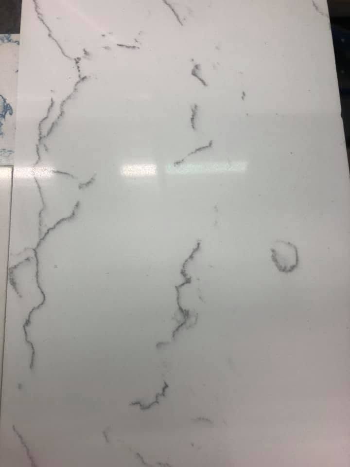 White marble-patterned surface with gray veining and a small circular mark on the right.