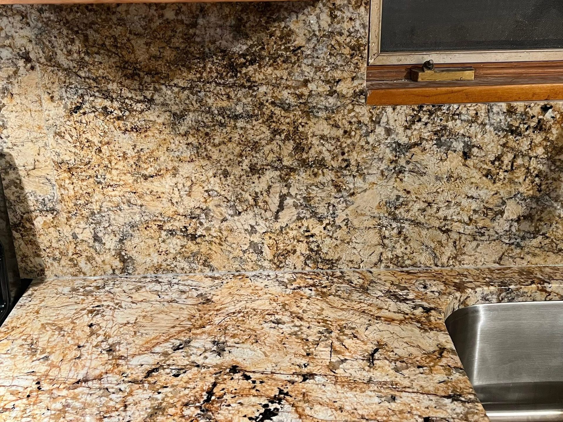 Granite kitchen countertop and backsplash with a stainless steel sink on the right