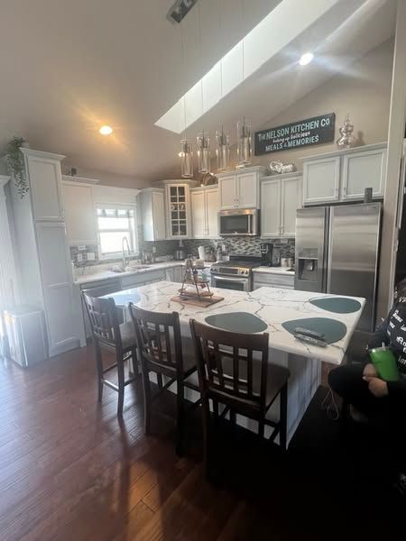 Bright kitchen with white cabinets, large island, stainless-steel appliances, and hardwood floors.