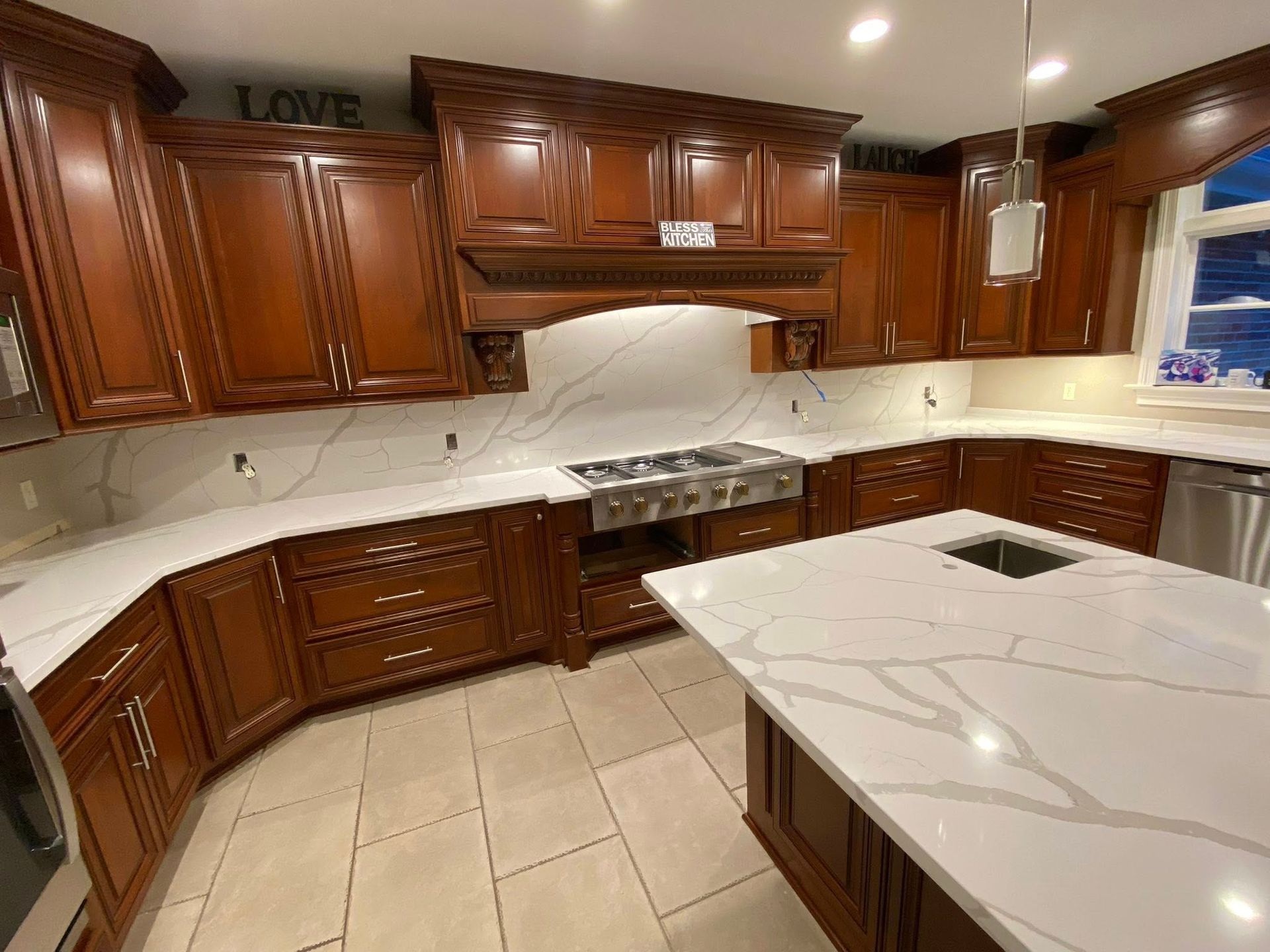 Elegant kitchen with dark wood cabinets, white marble countertops, and beige tile floor
