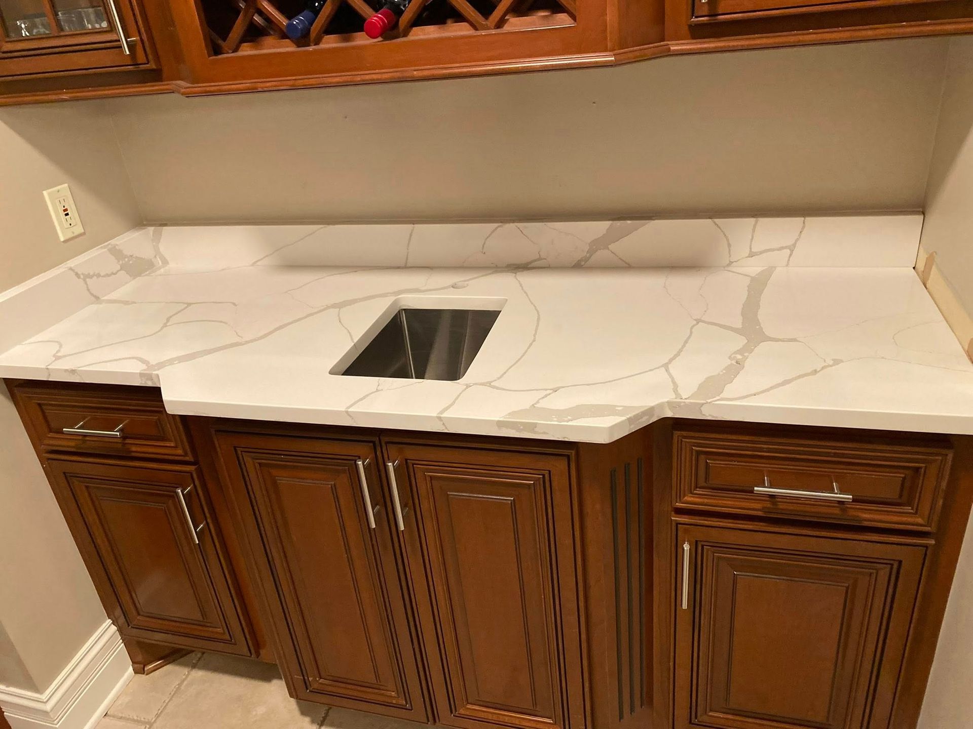 Kitchen countertop with white marble-look surface, undermount sink, and dark wood cabinets underneath