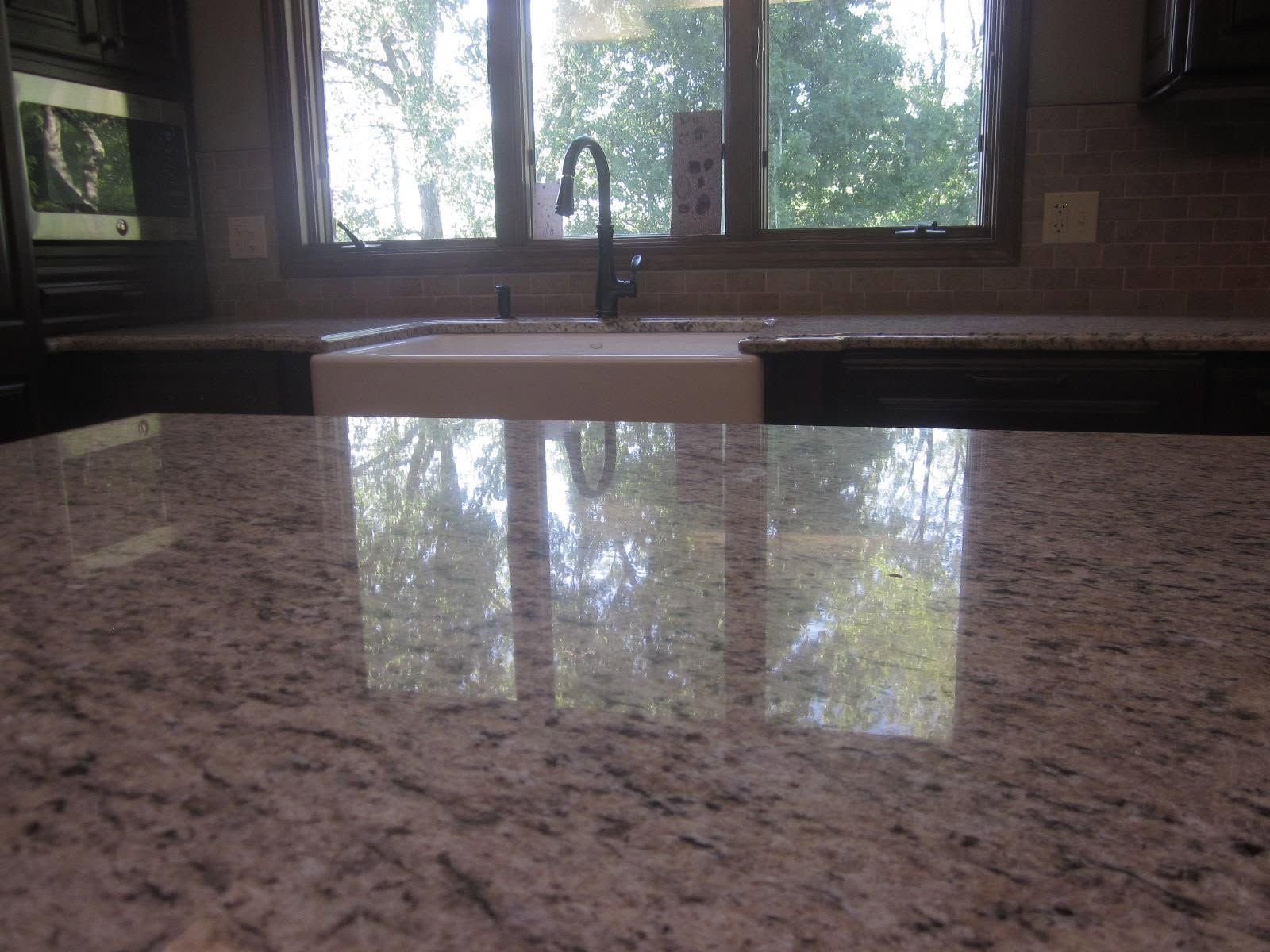 Kitchen with granite countertop and sink overlooking a bright window with trees outside.