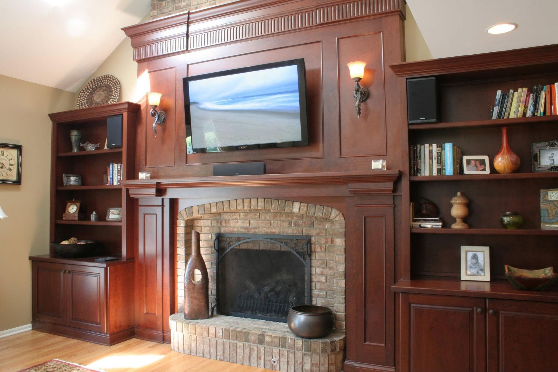 Wood-paneled living room with a fireplace, wall-mounted TV, and built-in bookshelves