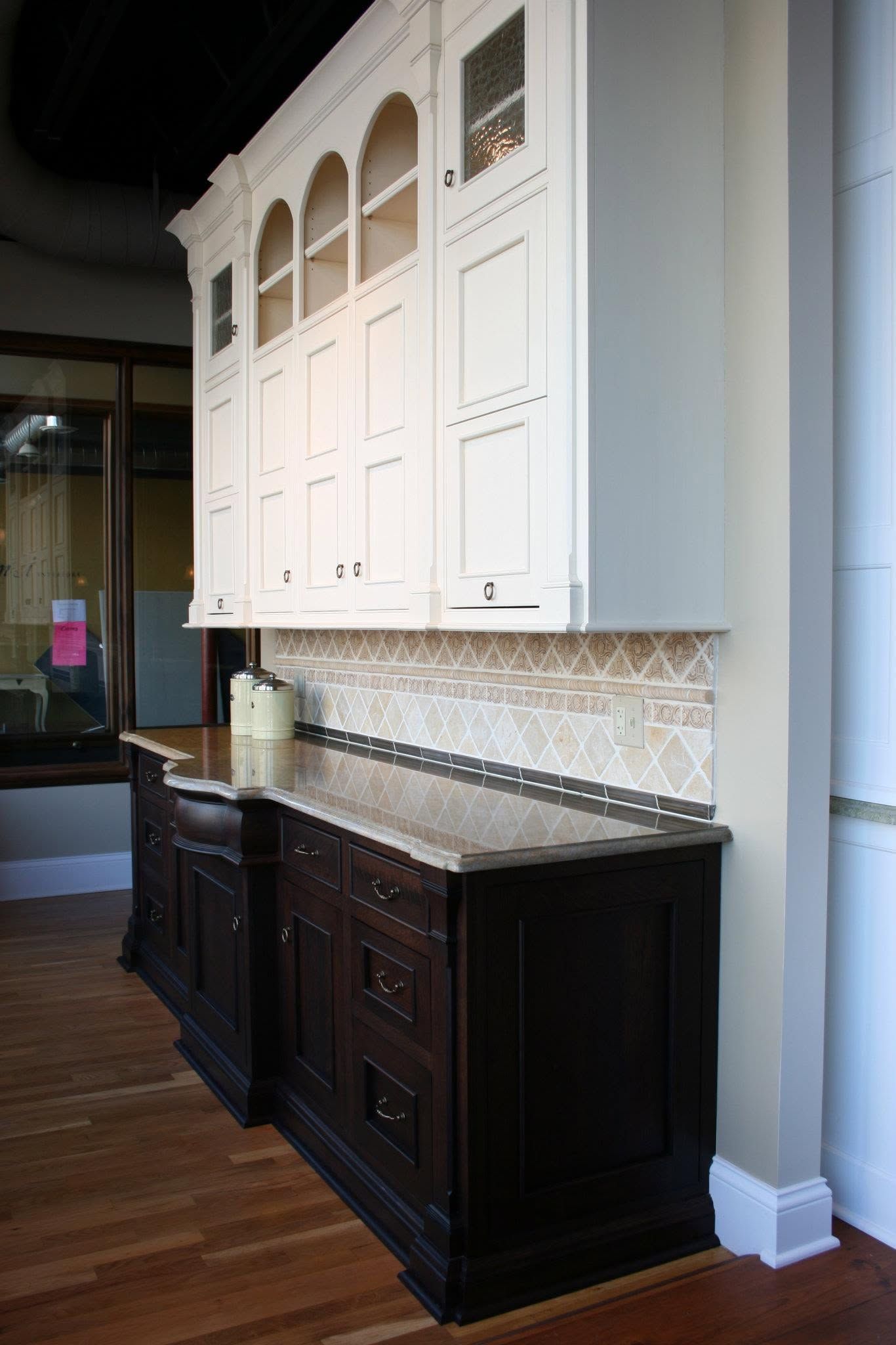 Elegant kitchen cabinetry with white upper cabinets, dark lower cabinets, and mosaic tile backsplash.