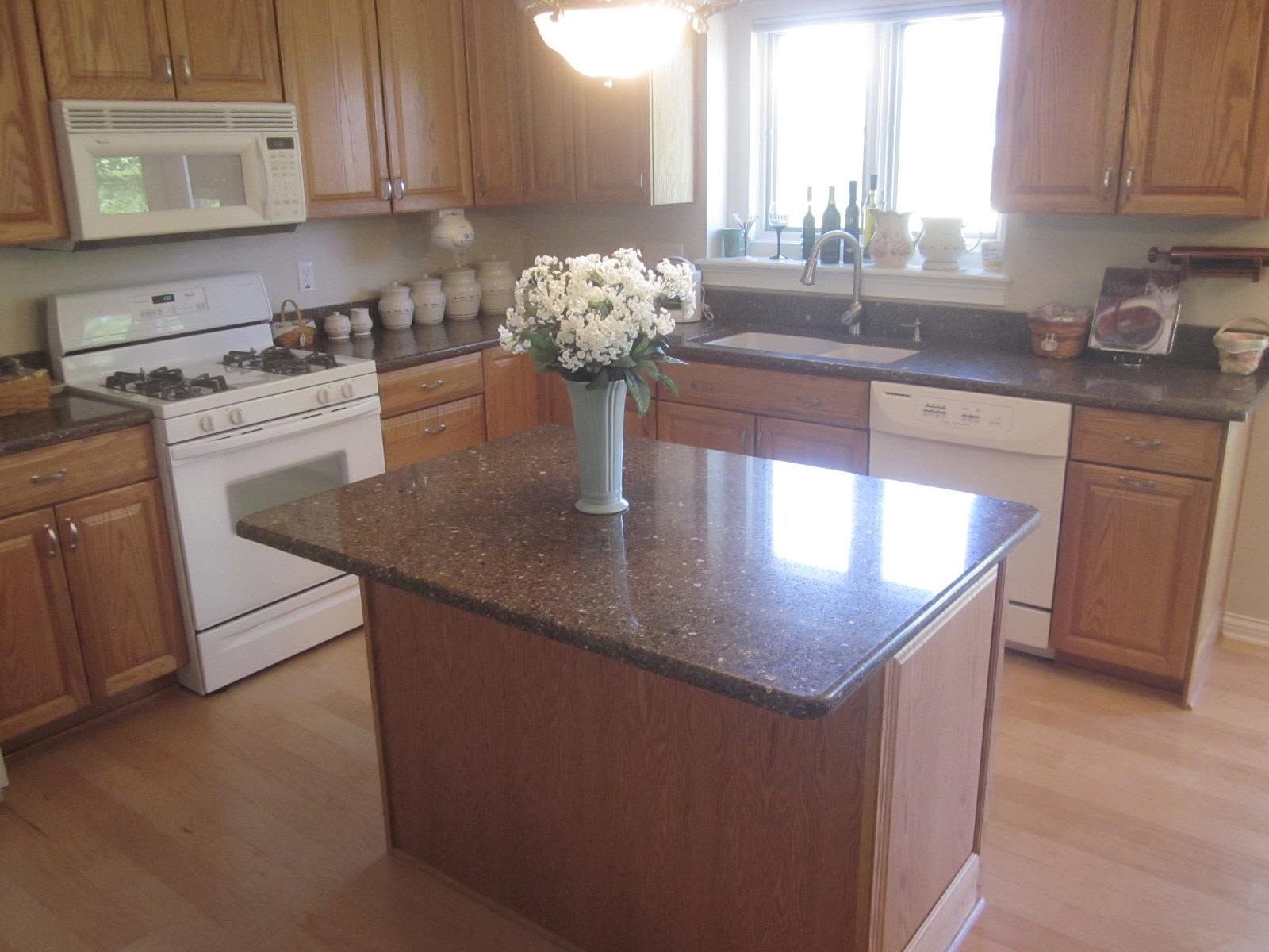 Kitchen with wood cabinets, white appliances, and a central island topped with flowers.