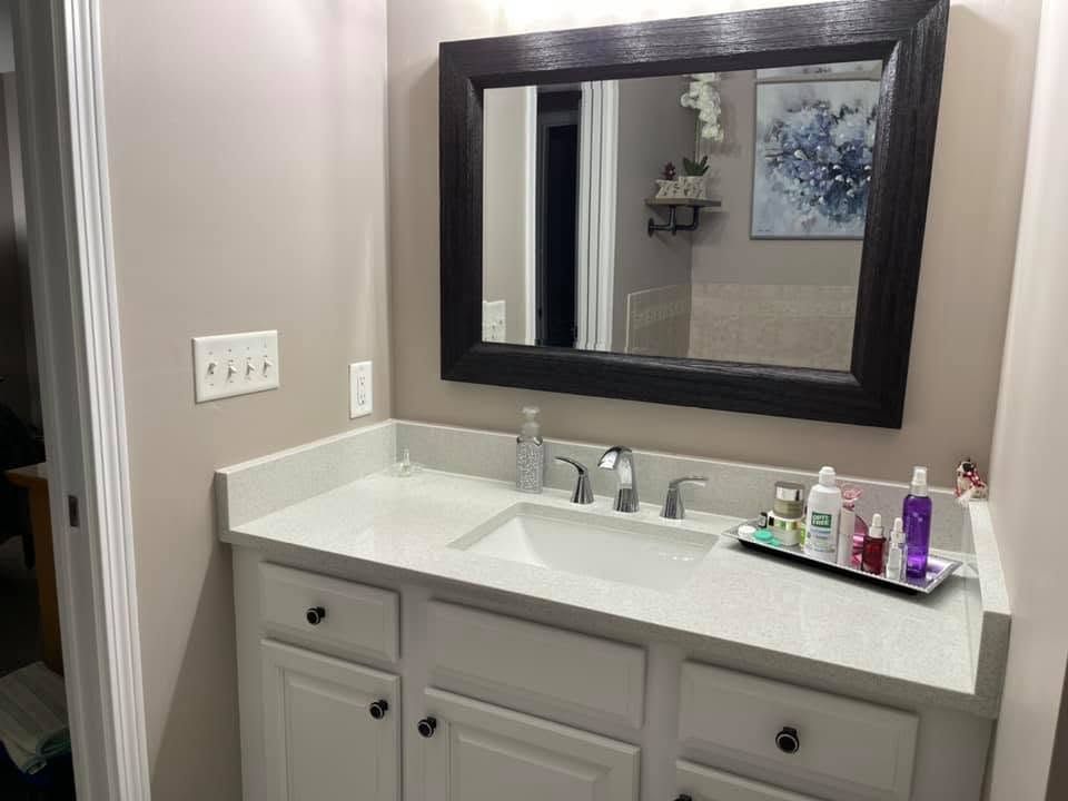 Bathroom vanity with sink, mirror, and countertop toiletries in a beige room