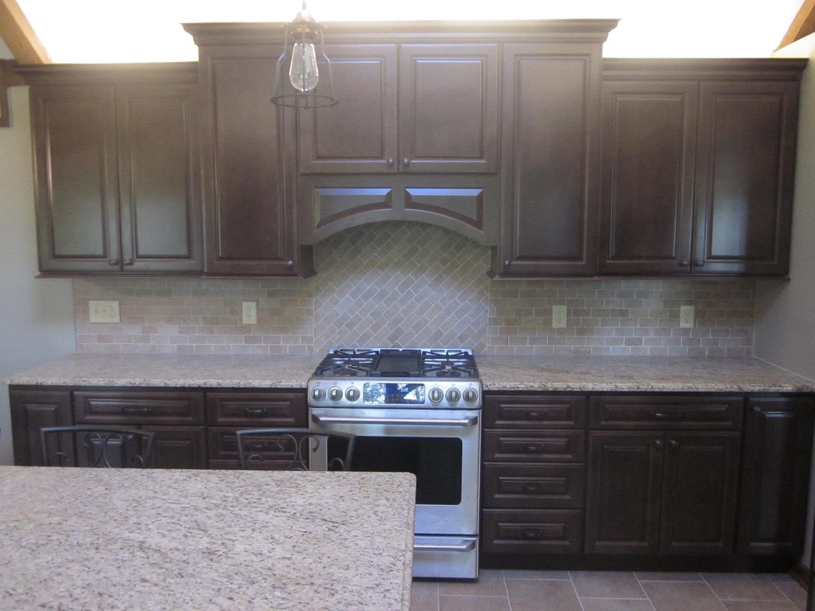 Dark wood kitchen cabinets, granite countertop, and stainless steel stove against a tiled backsplash.
