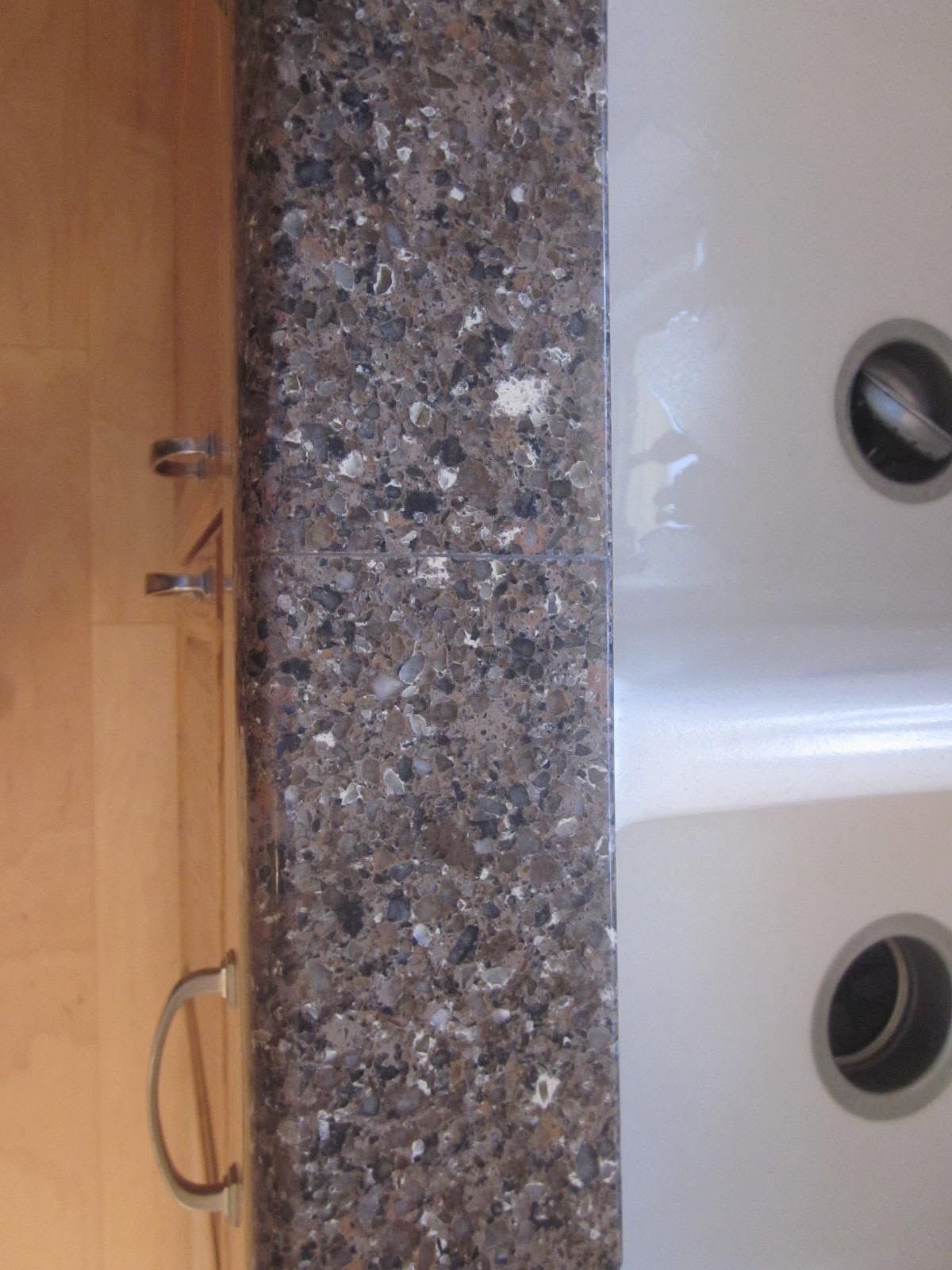 Bathroom vanity with speckled granite countertop, white sink, and wooden cabinet doors with curved handles.
