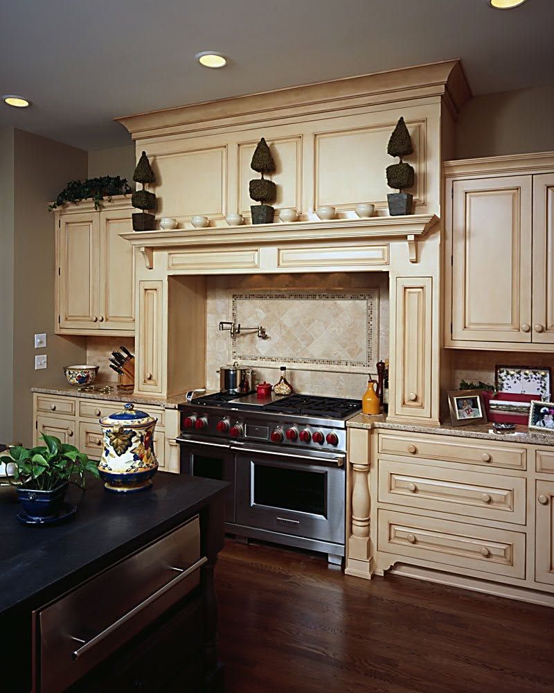 Elegant cream-colored kitchen with a stainless steel stove, built-in cabinets, and dark wood floor.