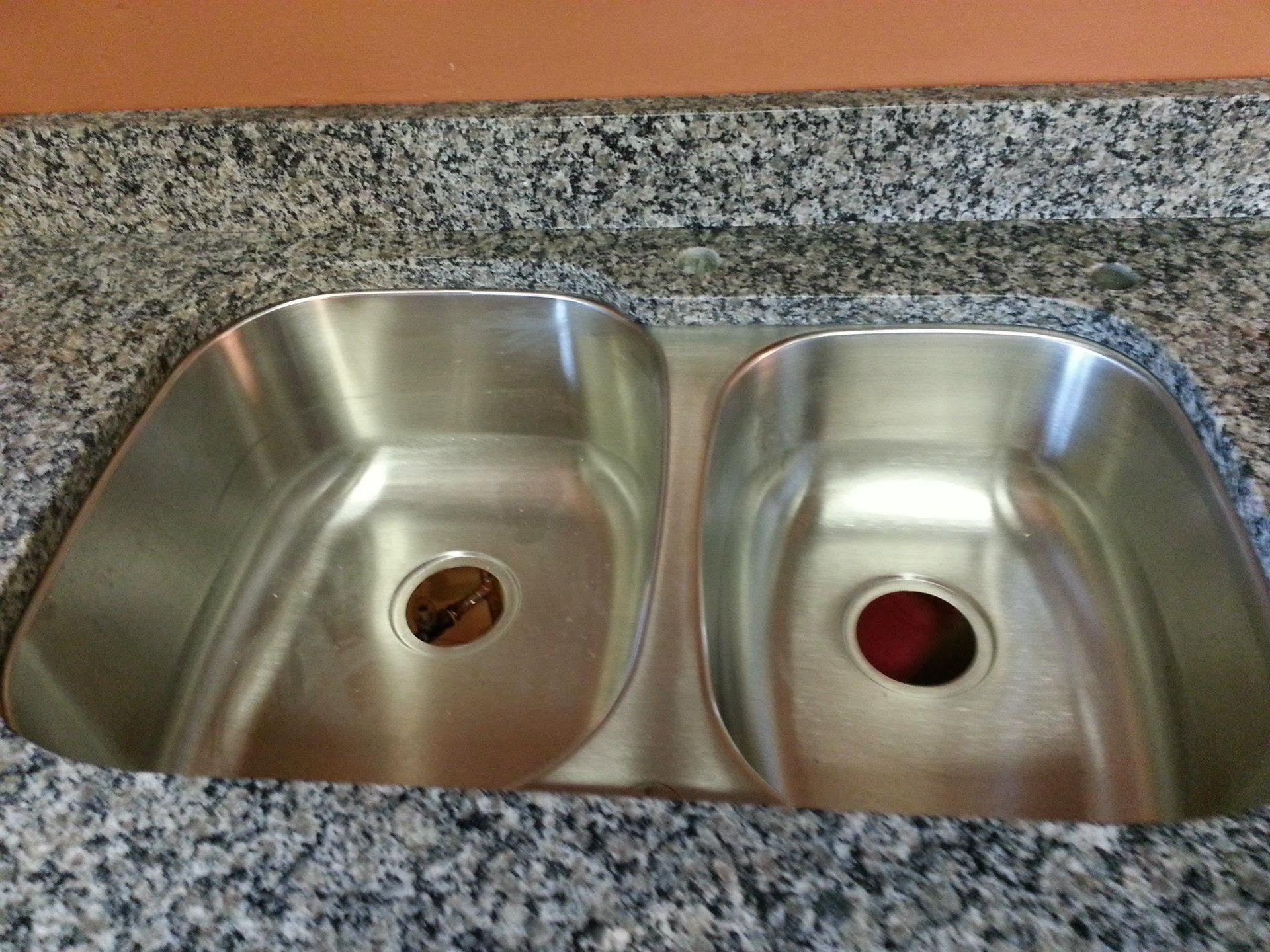 Double stainless steel kitchen sink set in speckled granite countertop