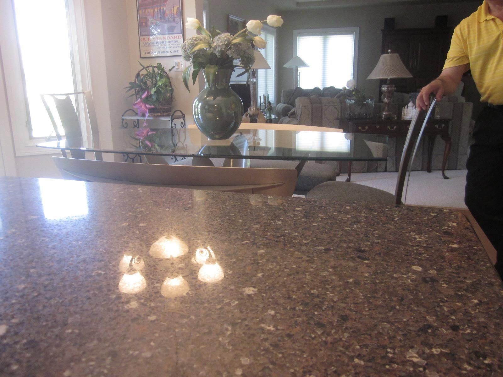 Kitchen countertop with a vase of flowers and a person holding a cane in the background