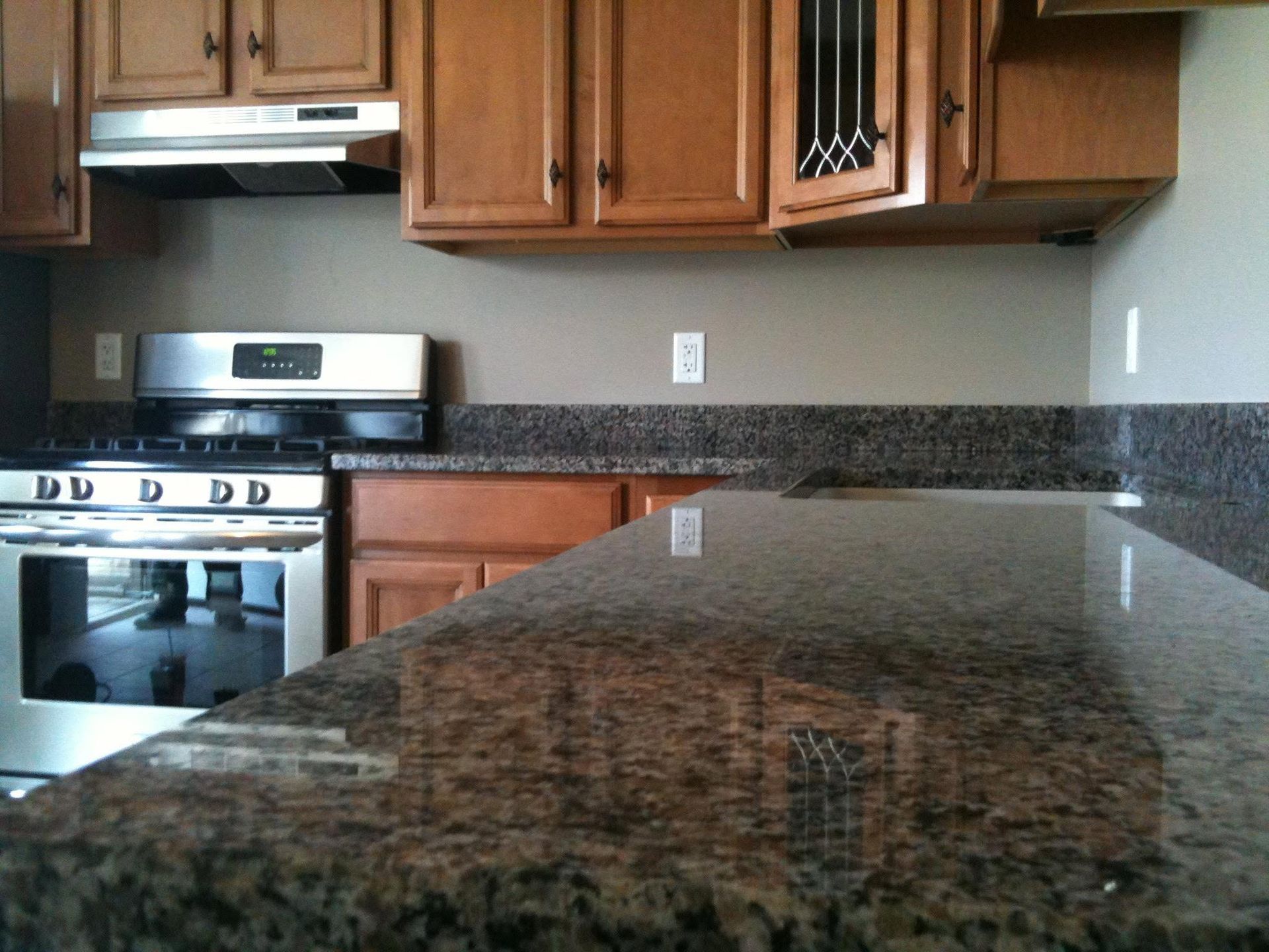 Kitchen with wooden cabinets, granite countertops, and a stainless steel stove.