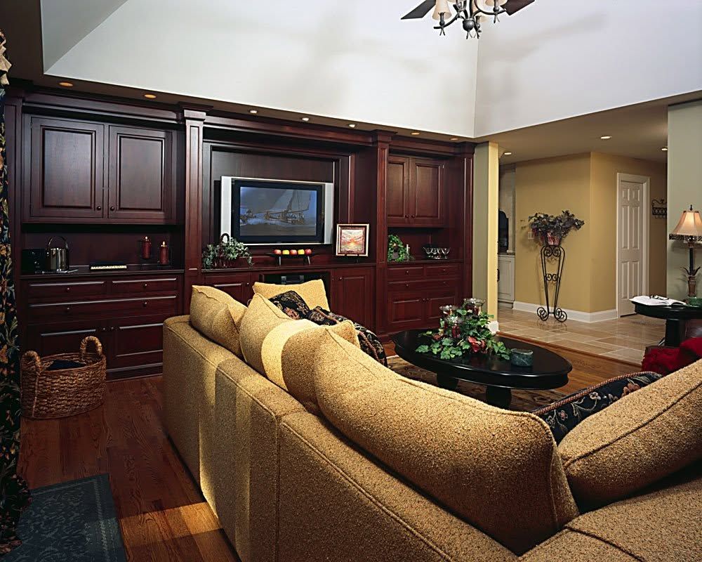 Elegant living room with dark wood built-ins, tan sofa, and a wall-mounted TV above a coffee table
