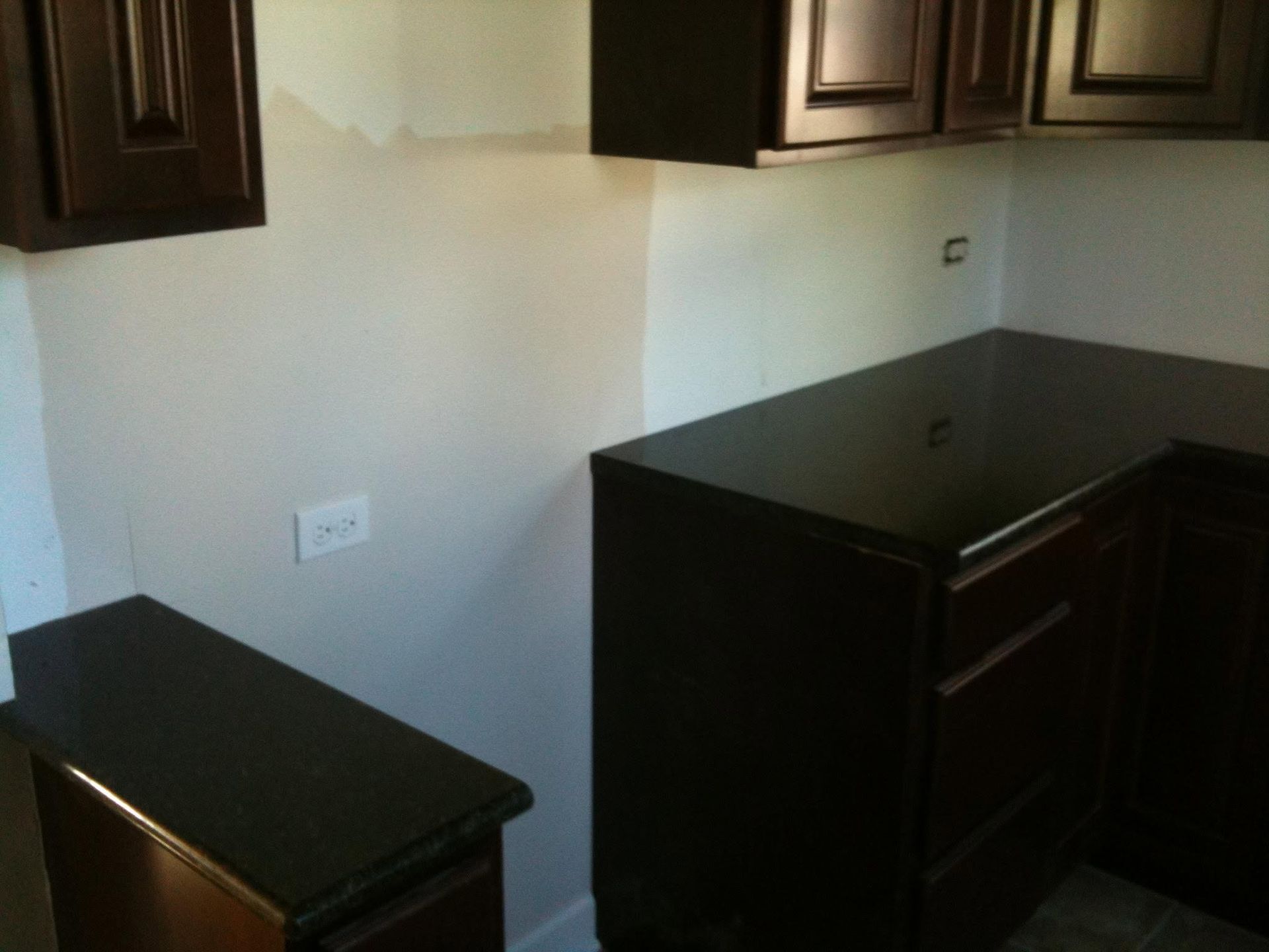 Empty kitchen with dark cabinets and black countertops along two walls