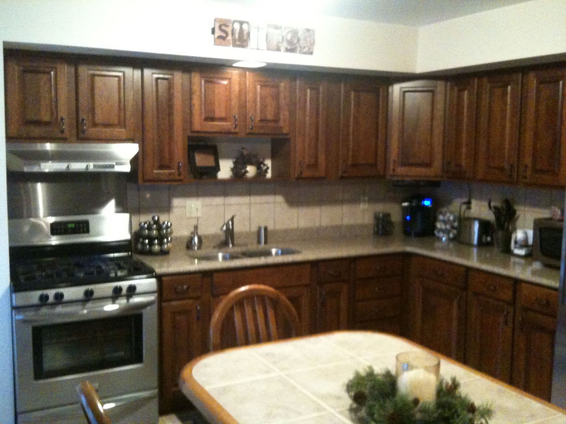 Wooden kitchen with stainless stove, dark cabinets, and a round table in the foreground