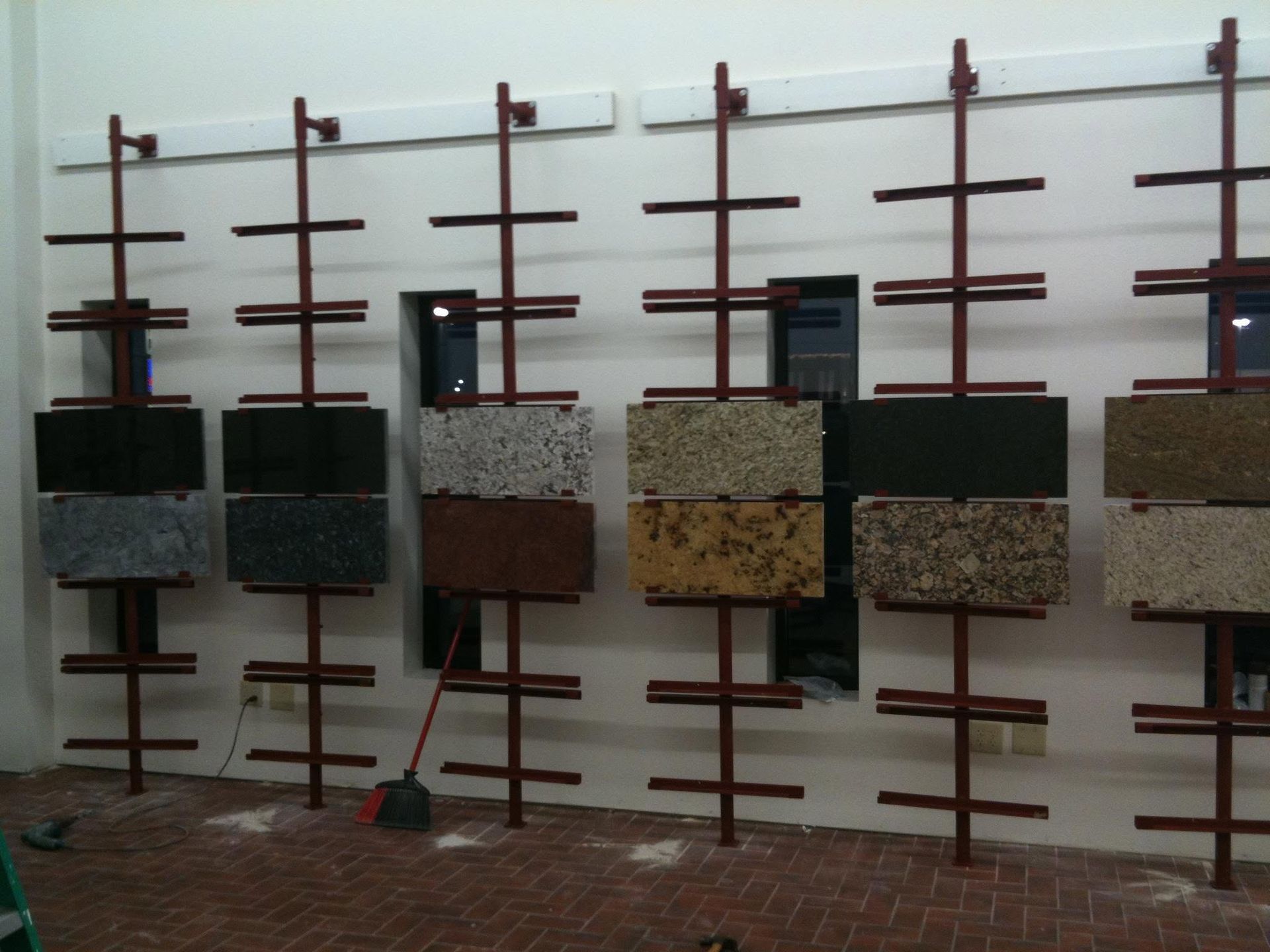 Row of wall-mounted birdhouses on a metal frame against a white wall outdoors