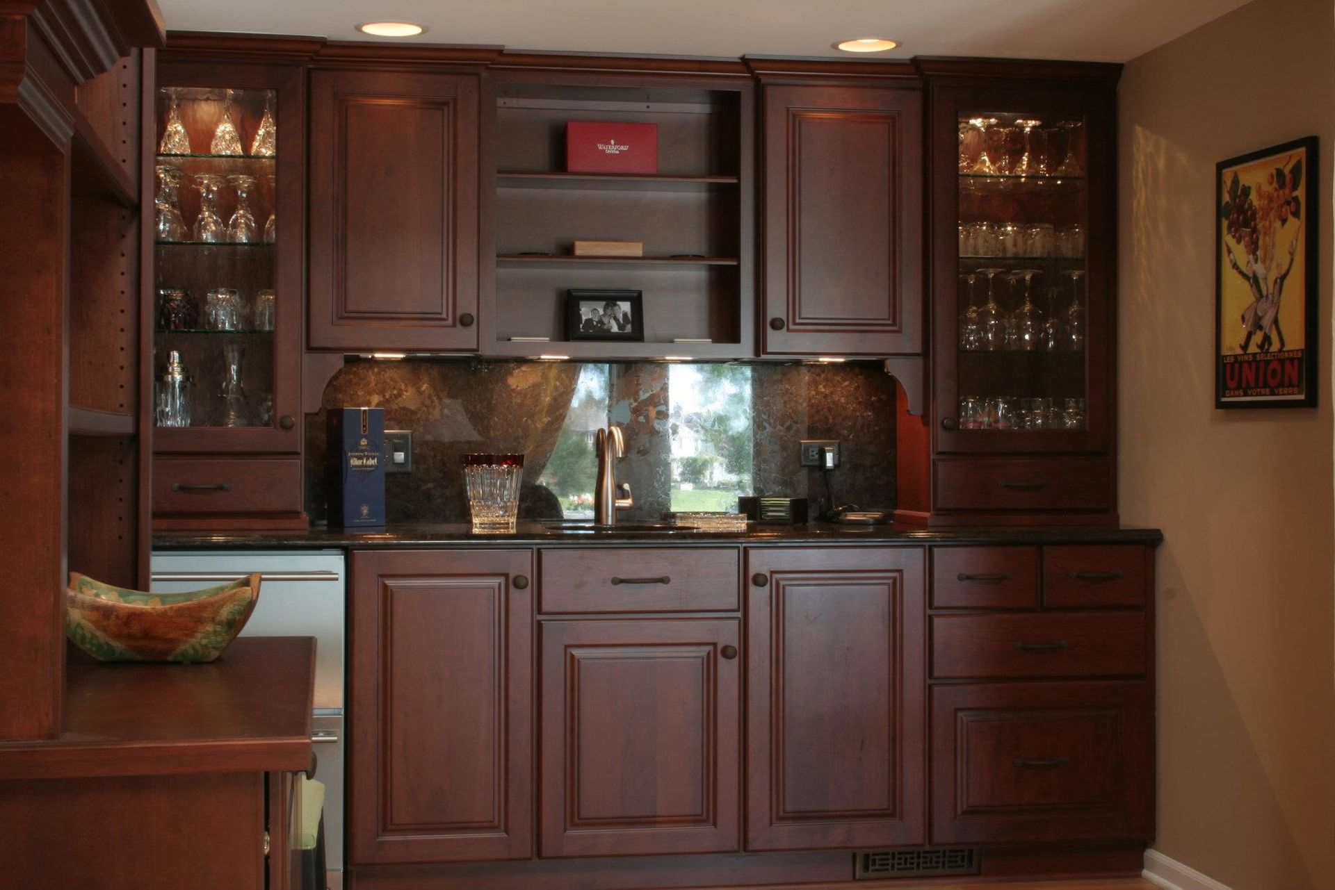 Built-in dark wood cabinets with glass doors, countertop, and sink in a warm kitchen wall unit