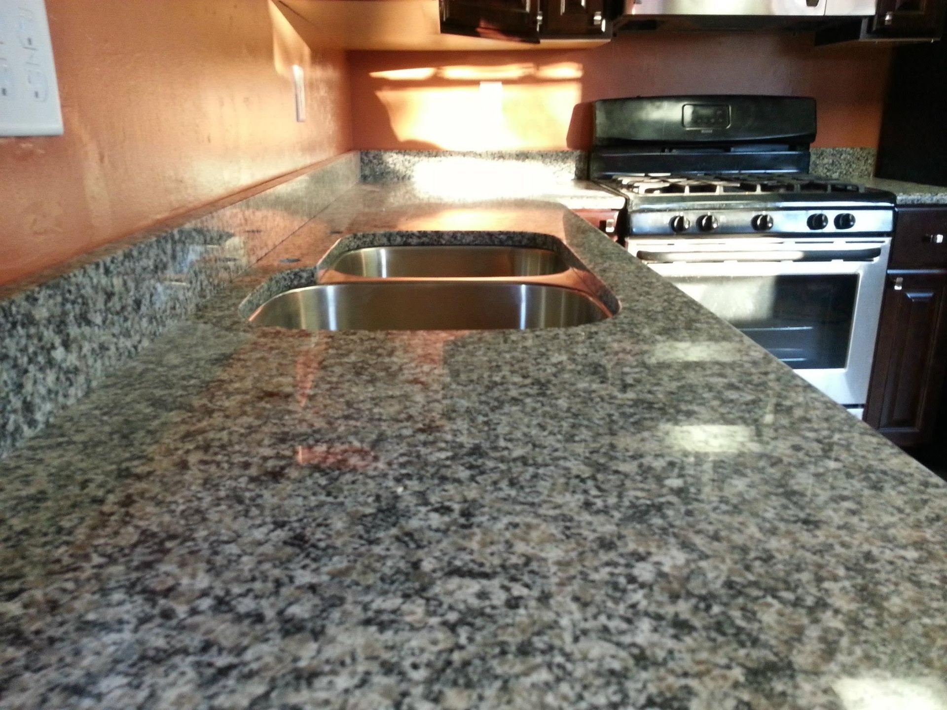 Kitchen countertop with double sink and stainless steel stove in the background