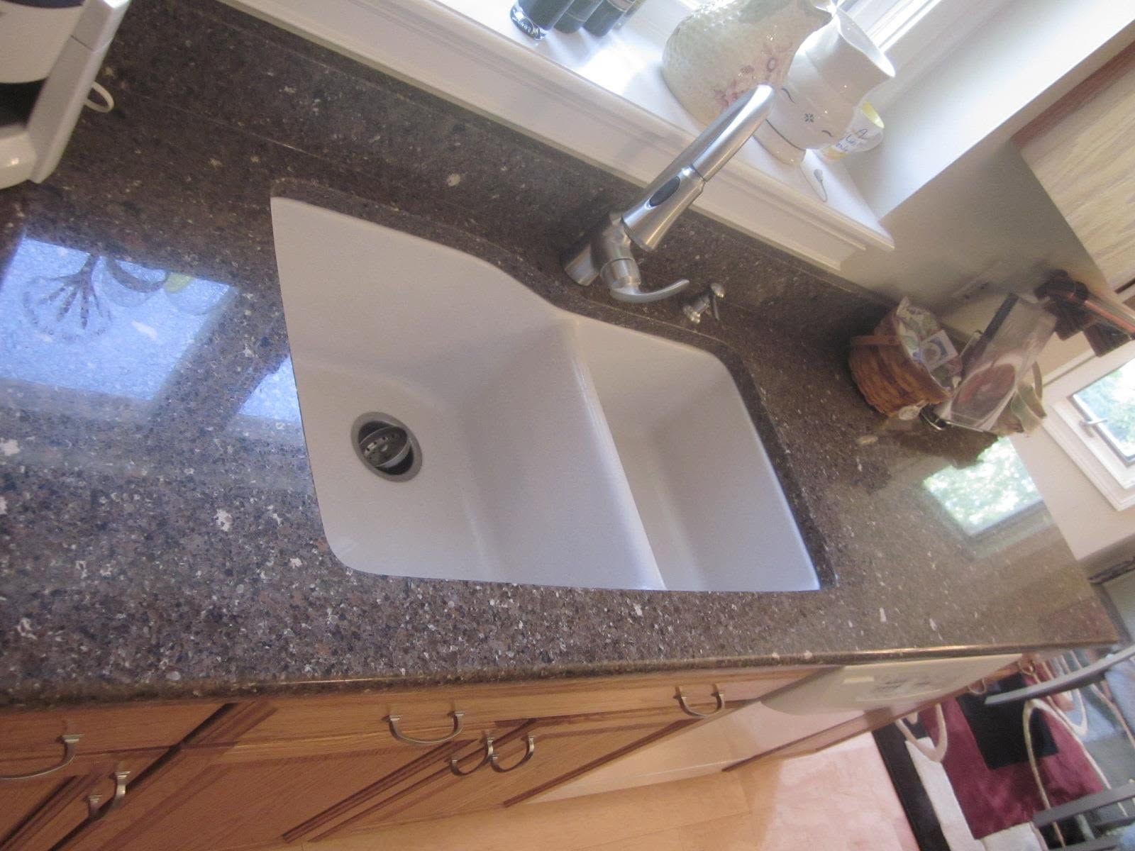 Granite kitchen countertop with a white sink and chrome faucet, viewed from above.