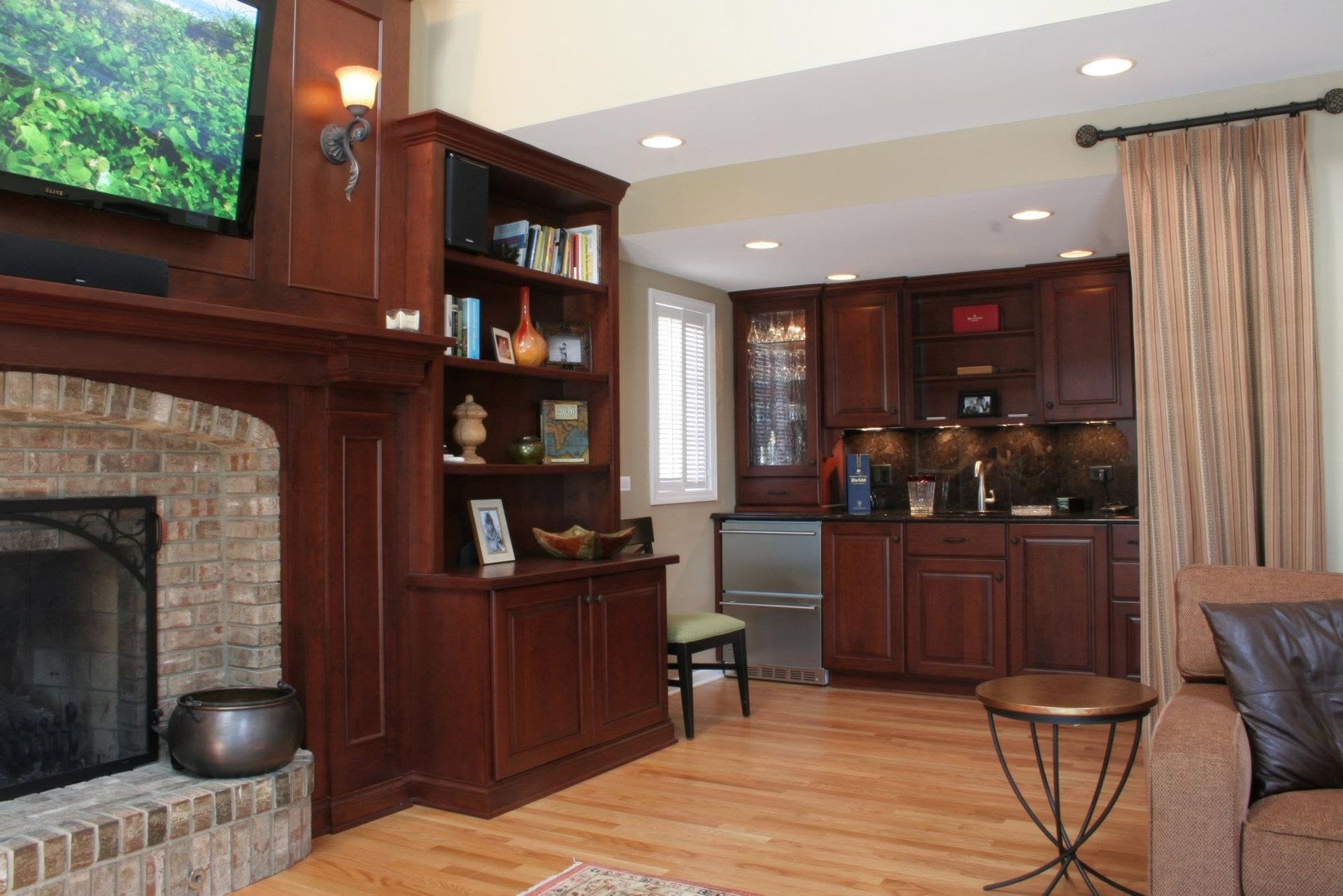 Cozy living room with fireplace, built-in shelves, wood cabinets, and TV above the mantel