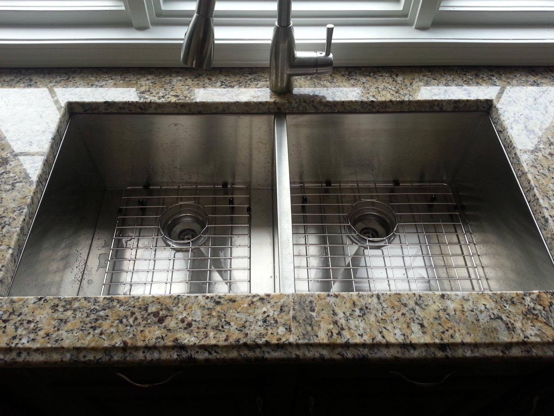 Double kitchen sink with granite countertop and window above