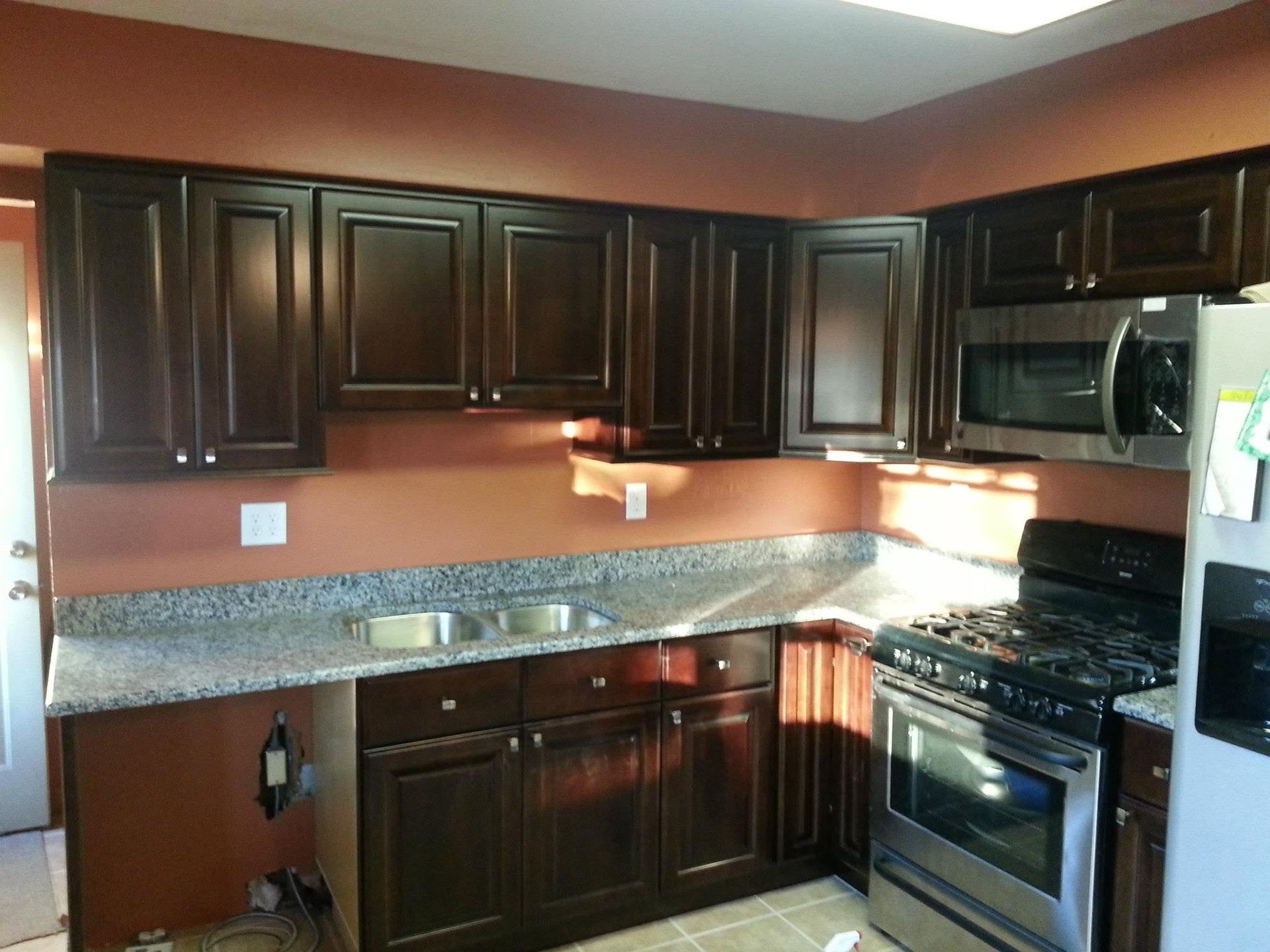 Dark wood kitchen cabinets with granite counters and stainless steel stove and microwave.