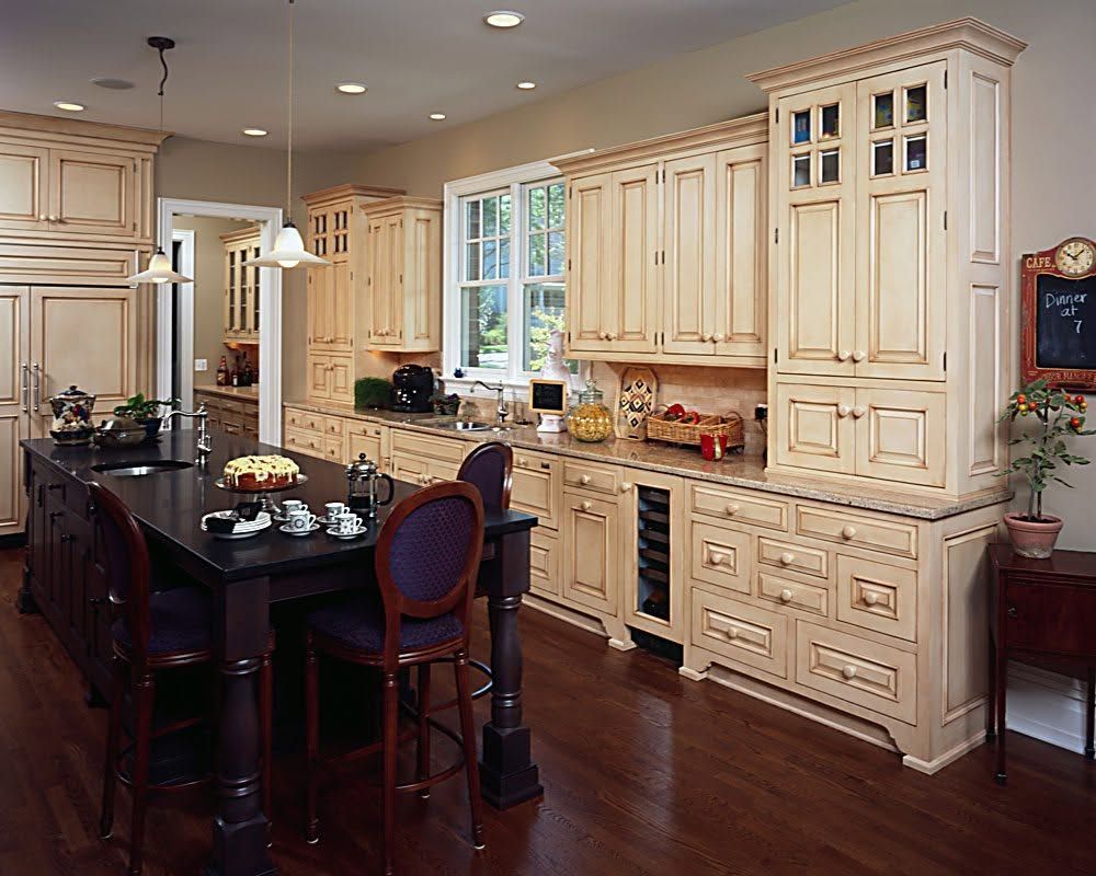 Bright kitchen with cream cabinets, dark wood island, and black countertop under a window.