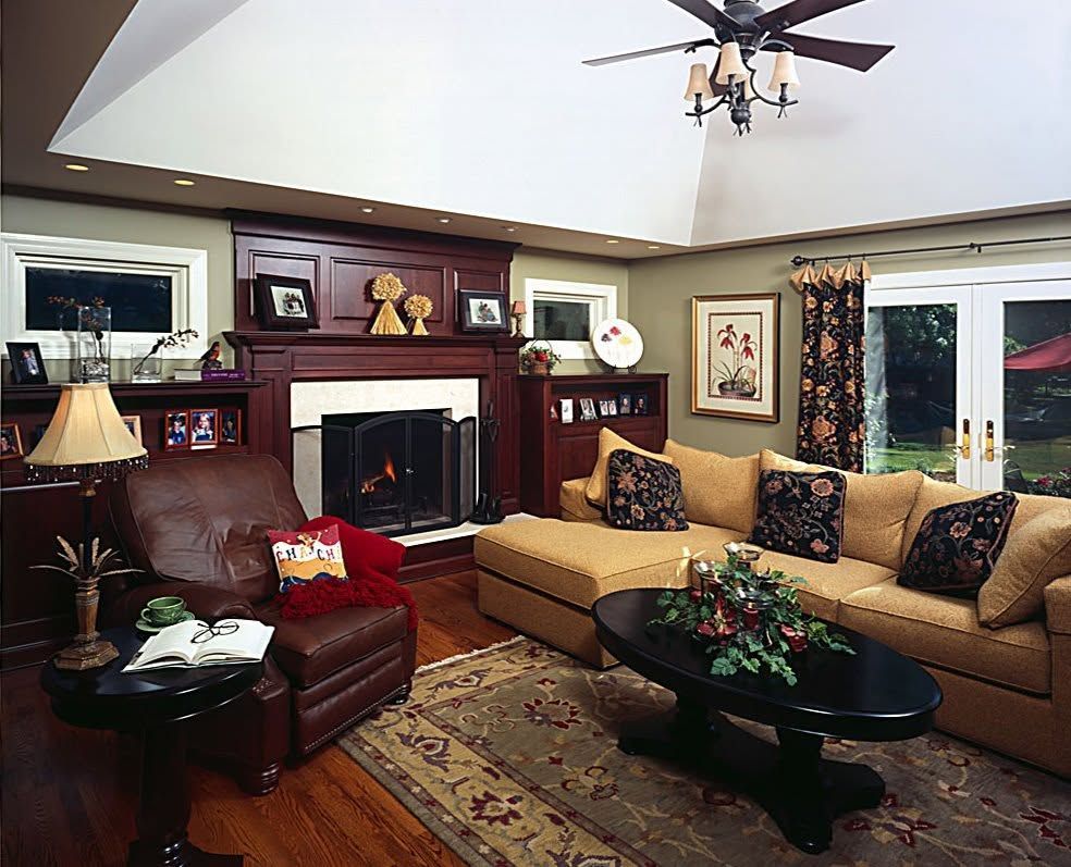 Cozy living room with fireplace, tan sofa, leather chair, coffee table, and ceiling fan