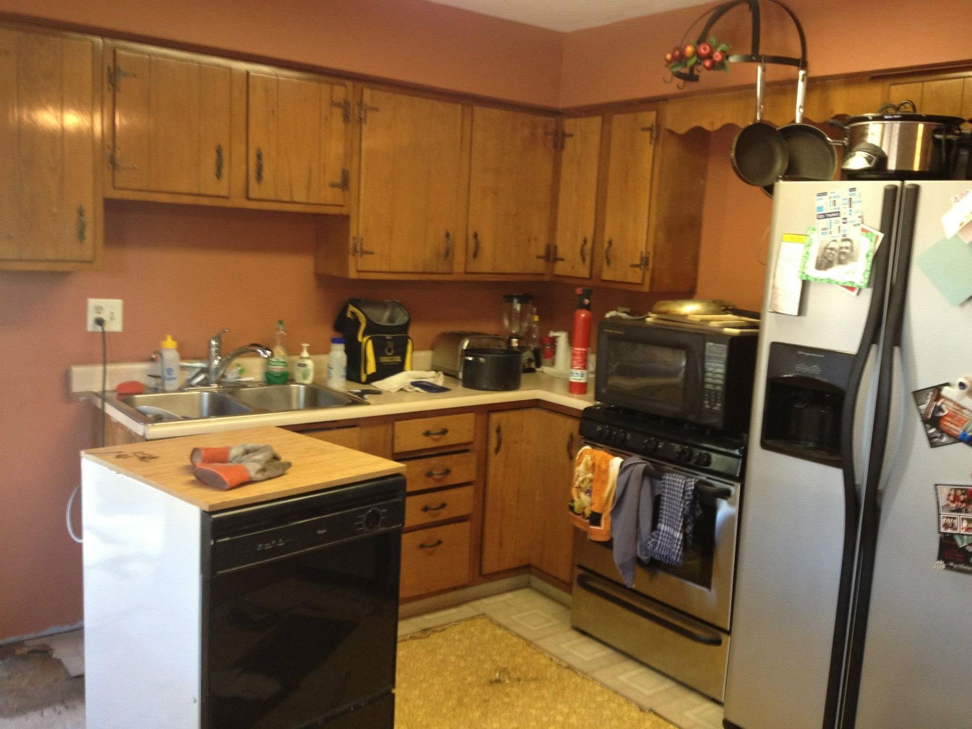 Small kitchen with wooden cabinets, white appliances, black dishwasher, and stainless steel refrigerator.