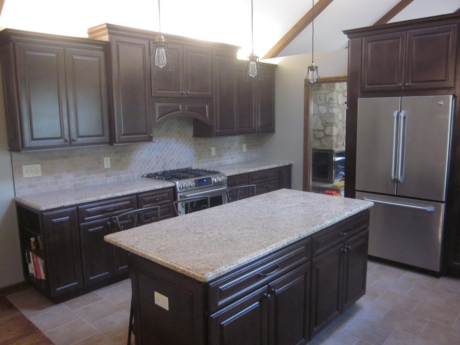 Modern kitchen with dark wood cabinets, stainless steel appliances, and a central island with granite countertop