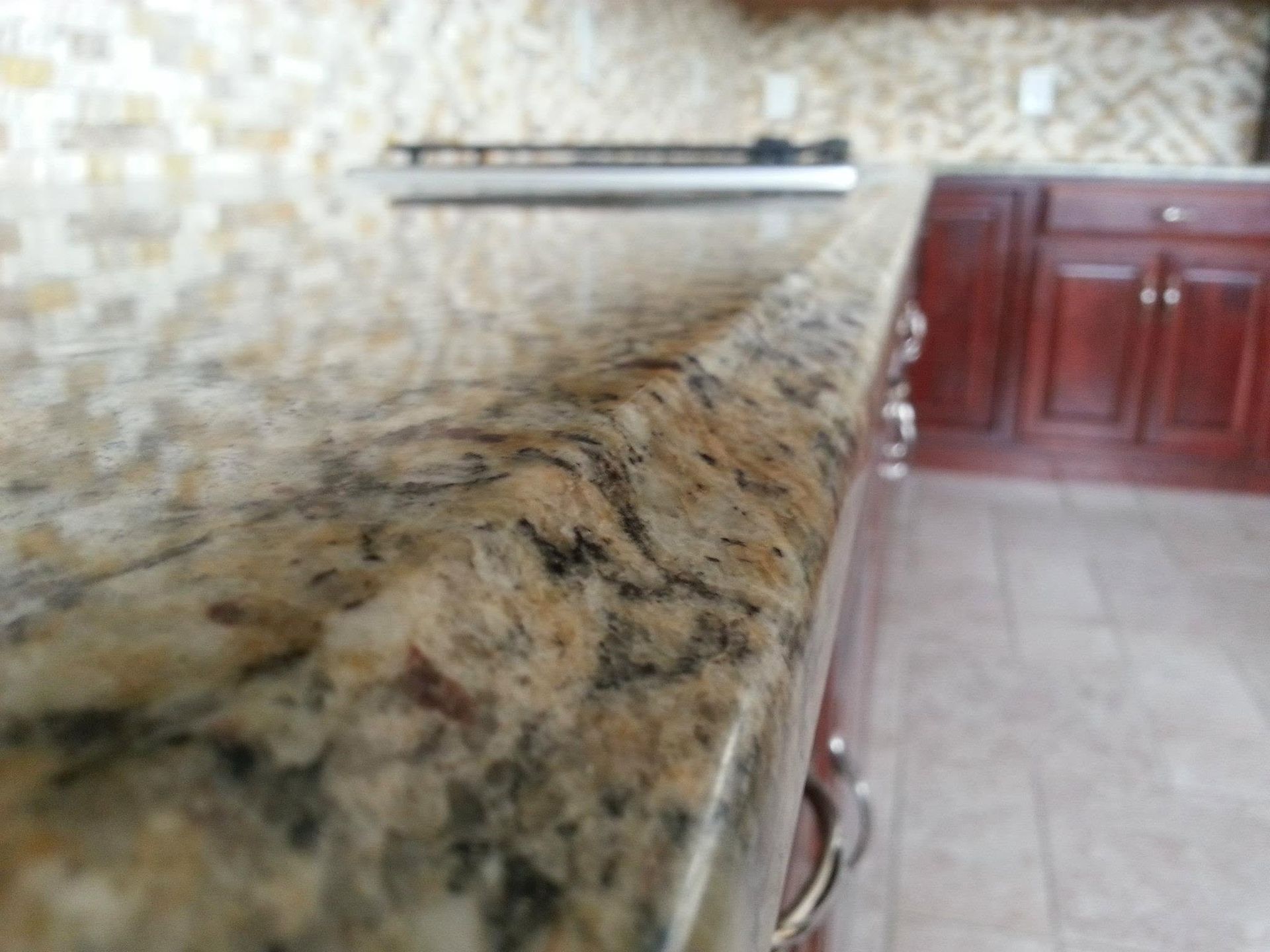 Granite kitchen countertop with backsplash and wooden cabinets in the background