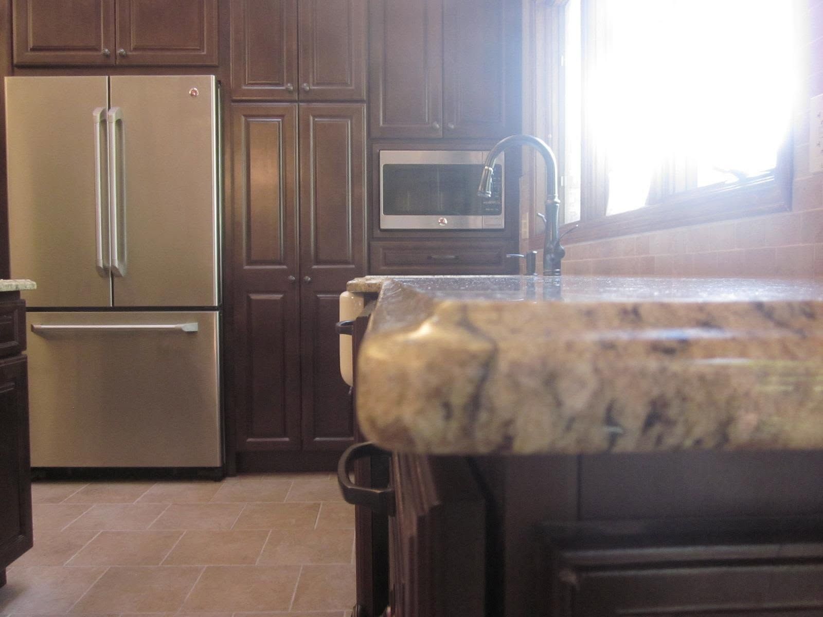 Kitchen with stainless steel fridge, wood cabinets, granite counter, and bright window light