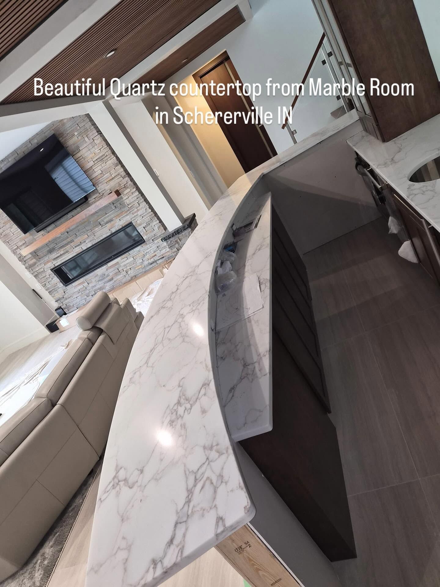 Modern marble-room interior with a white quartz countertop and dark cabinetry, viewed at an angle