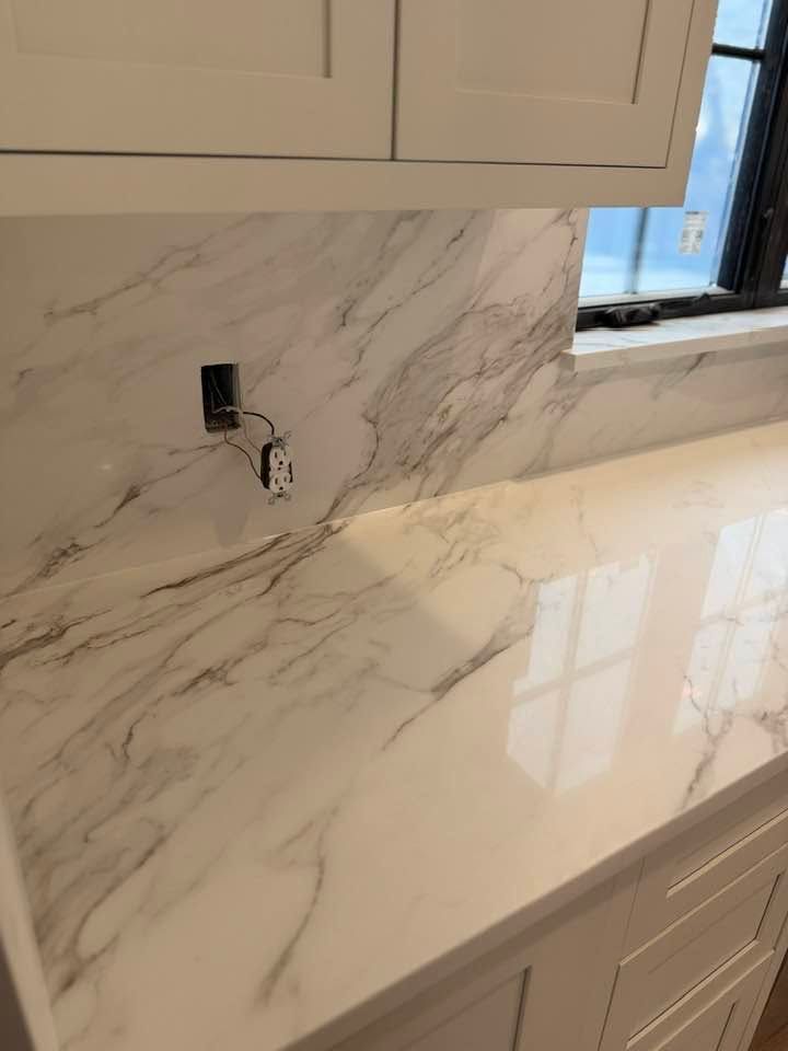 Marble kitchen countertop with backsplash, outlet, and window on the right