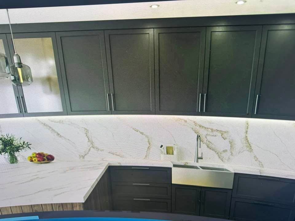 Modern kitchen with dark cabinets, white marble countertops, and stainless steel sink.