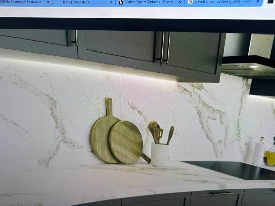 Modern kitchen with gray cabinets, white marble backsplash, and cutting boards on the counter